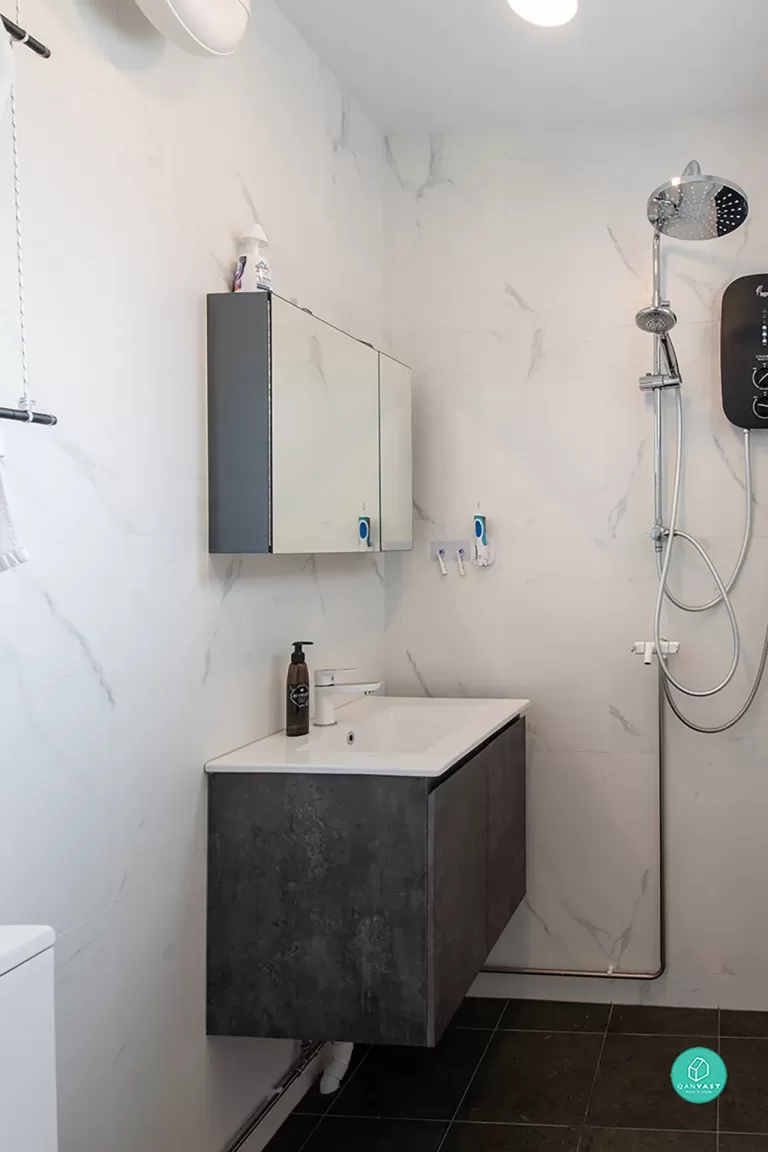 Modern minimalist HDB bathroom at 114 Bishan St 12. Features high-contrast design with glossy white marble-look wall tiles, matte dark charcoal floor tiles, and a floating vanity cabinet for maximum space in a compact Singapore flat.