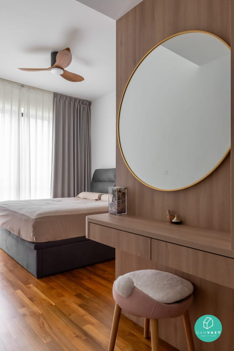 Modern contemporary bedroom with wooden floating makeup table, round mirror, cushioned stool, beige sheets, ceiling fan, large window with sheer curtains. Warm, bright, airy.