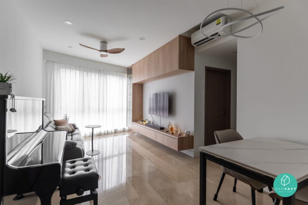 Modern contemporary living room with a piano, sofa, TV on a wooden wall unit, ceiling fan, air conditioner, dining table, and large windows letting in bright natural light.