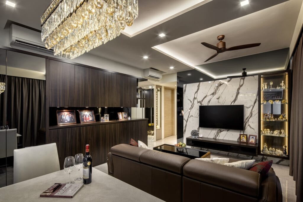 Modern luxury living room at Sennett Residence with crystal cascade chandelier, Calacatta-style marble TV feature wall, dark walnut veneer carpentry and brown leather sofa The crystal cascade chandelier anchors the open-plan living and dining zone, with a book-matched marble feature wall framing the television.