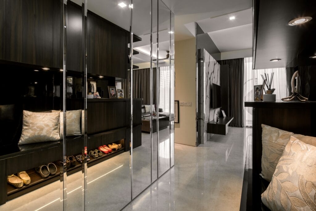 Mirrored full-height shoe cabinet with integrated bench seating and concealed footwear storage at Sennett Residence condominium foyer A full-height mirrored shoe cabinet with integrated bench and lit display niche turns a tight foyer into a graceful arrival sequence.