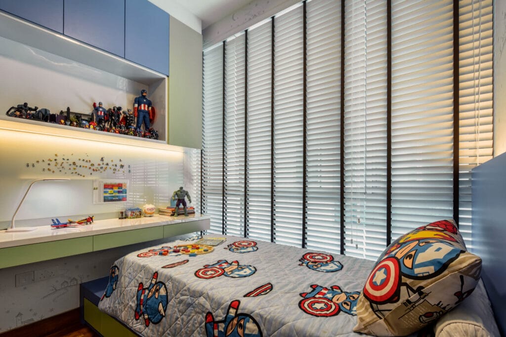 Second children's bedroom at Sennett Residence with sage green and dusty blue palette, full-length white quartz study counter, lit display ledge and Avengers-themed bedding The second bedroom in a softer sage and blue palette — same custom-build philosophy, calmer mood.