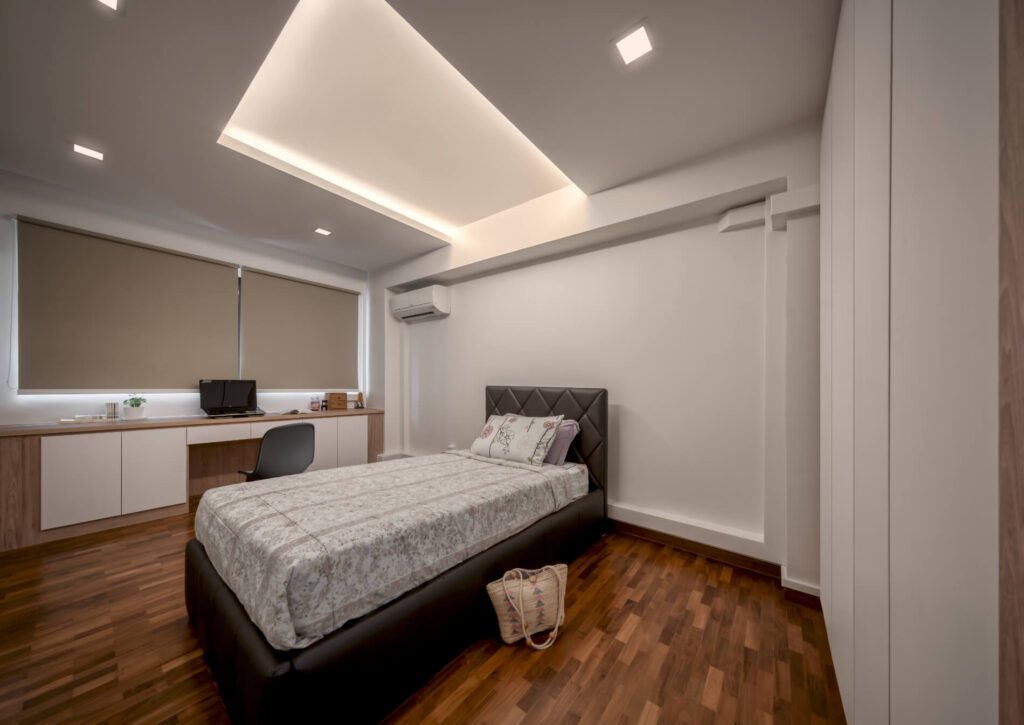 Junior bedroom with full-length study desk, backlit LED niche and white wardrobes in a Pasir Ris HDB flat
