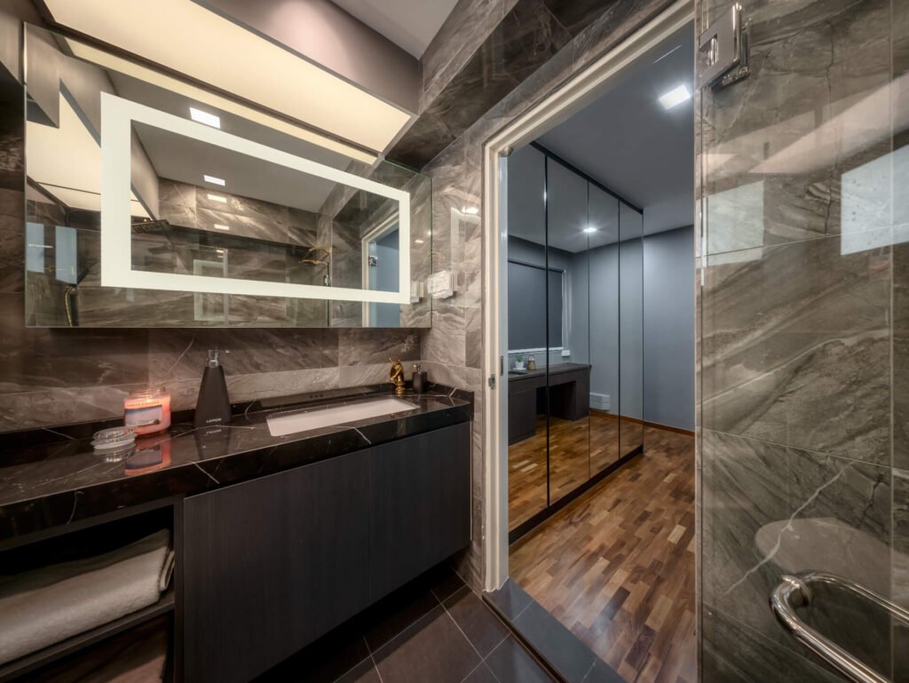 Master bathroom with grey marble-look tiles, black marble vanity top and gold fittings in a Pasir Ris 5-room HDB