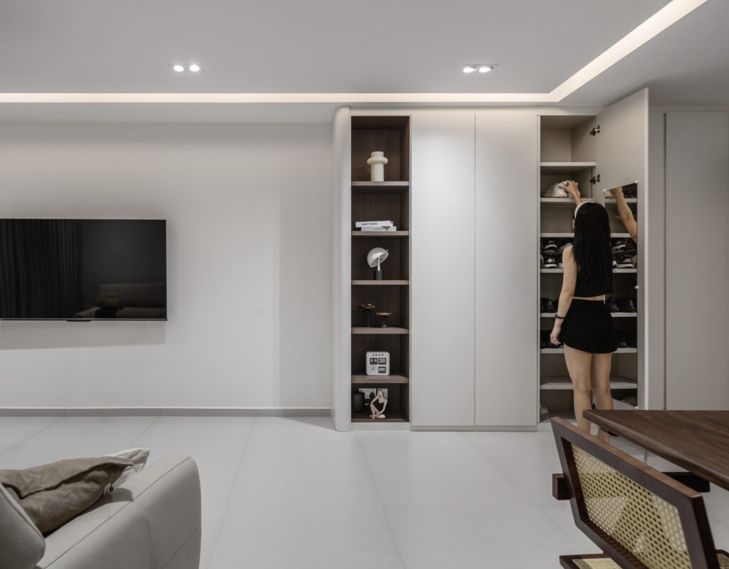 Stylish cream minimalist living room showcasing a full-height built-in cabinet, featuring modern furnishings and natural light.