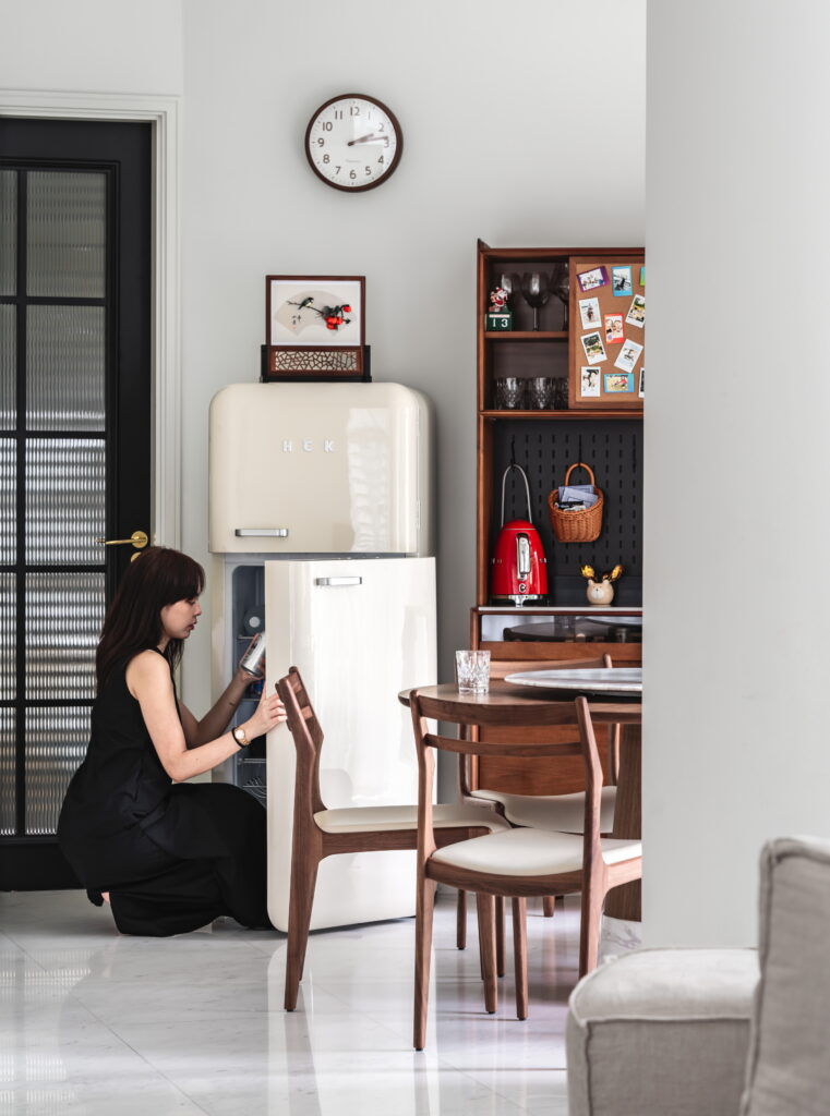 A lady arranging food inside a modern yet classic fridge, blending sleek design with timeless elegance, perfect for a stylish kitchen.