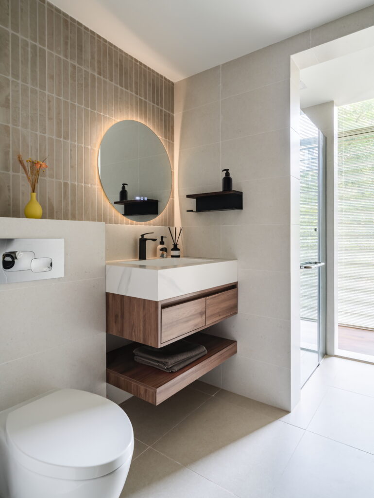 A mid-century modern bathroom with a floating vanity, round mirror, and tiled walls, highlighting clean lines and stylish functionality.