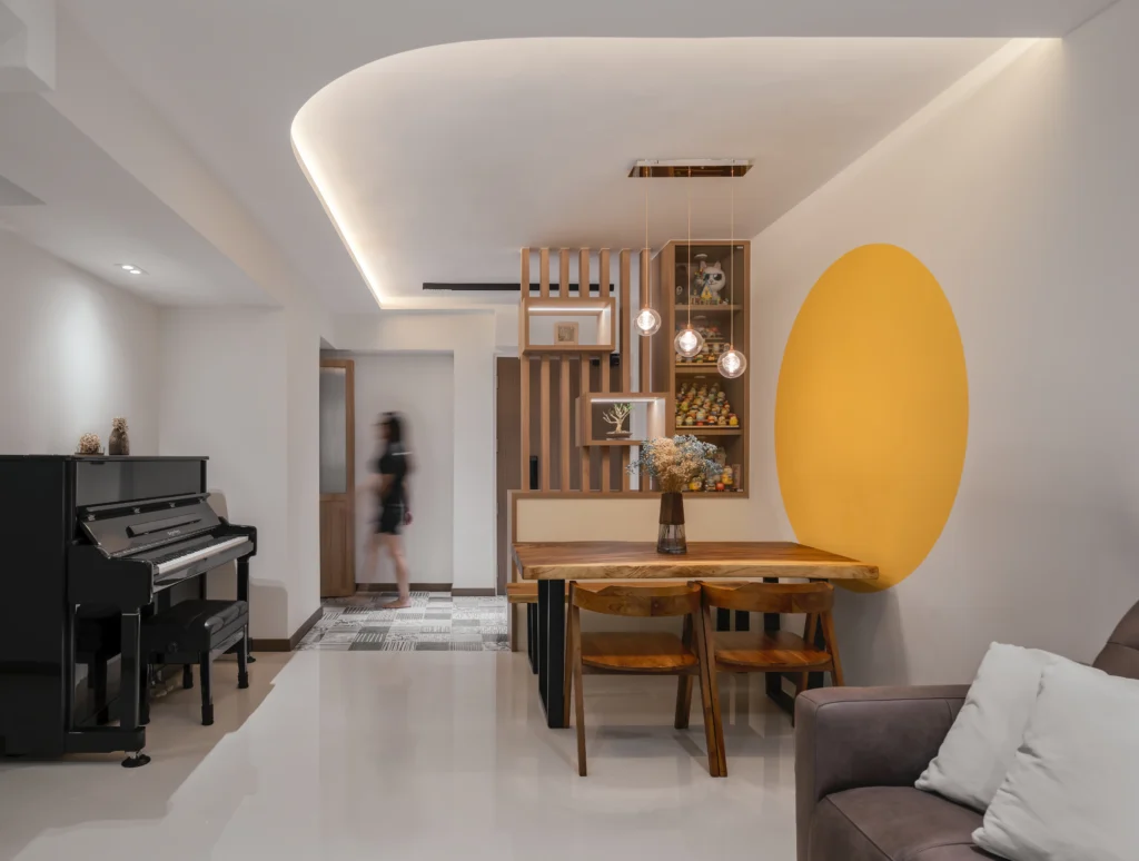 Contemporary Scandinavian living room with piano, wooden dining table, yellow accent wall, and a person walking in the background.