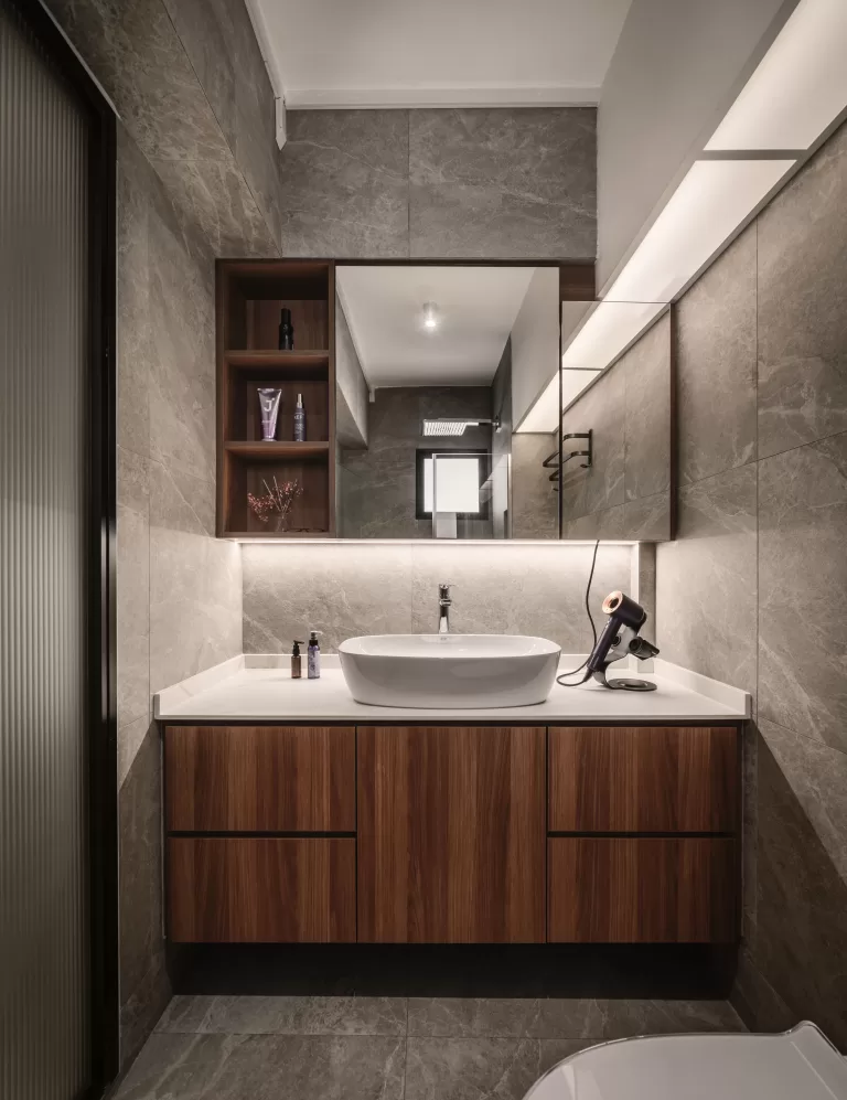 A detailed shot of a bathroom vanity showing the contrast between a dark wood cabinet and a white vessel sink.