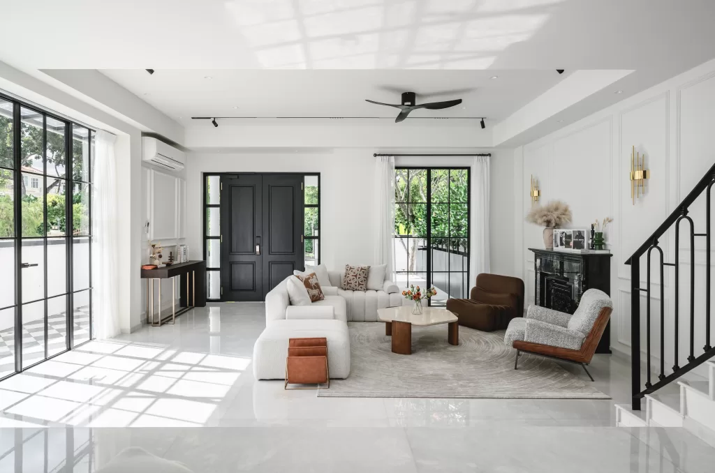 Modern Victorian living room with marble coffee table, brown armchairs, black fireplace, and arched windows at Lorong J Telok Kurau.