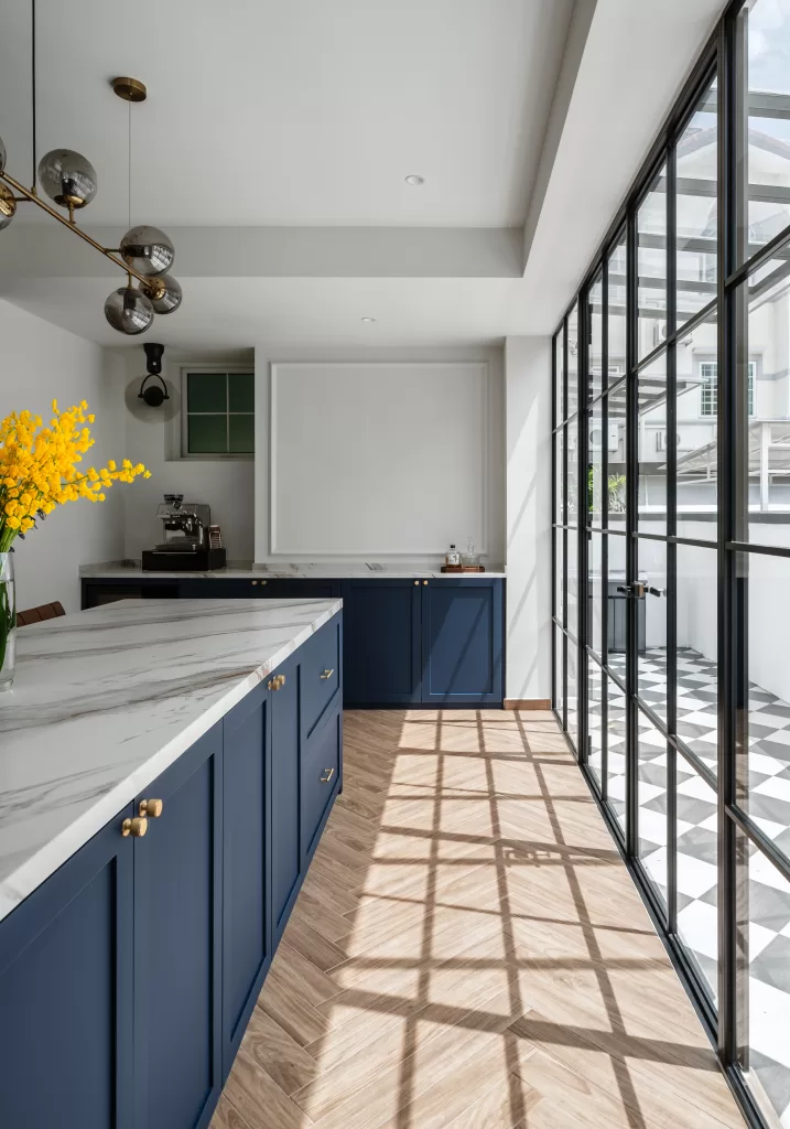 Modern Victorian kitchen design: navy blue cabinets, gold handles, herringbone wood floors, and natural light at Lorong J Telok Kurau.
