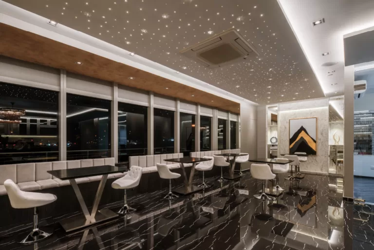 Elegant office lounge interior with glossy black marble flooring, sleek black tables, white cushioned chairs, and large windows showcasing city light views at 37 Jalan Pemimpin.