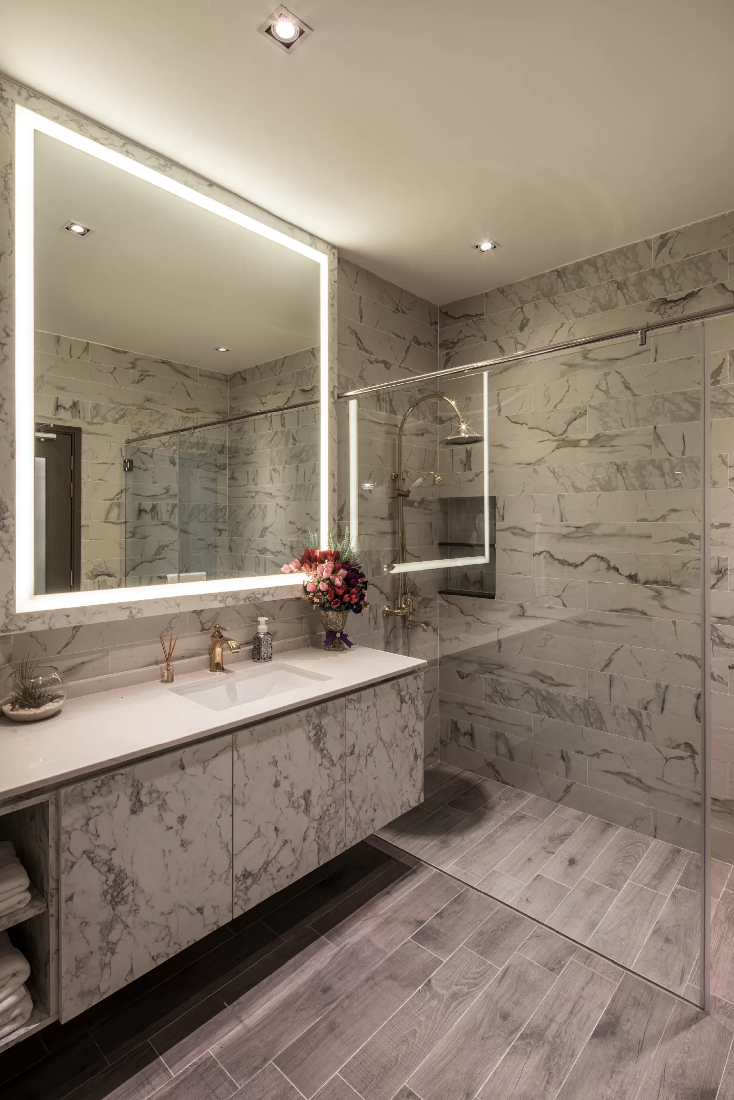 Luxurious bathroom at 37 Jalan Pemimpin featuring marble walls, gold fixtures, a glass-enclosed shower, and an illuminated mirror with an LED light in toilet area, complemented by elegant floral decor