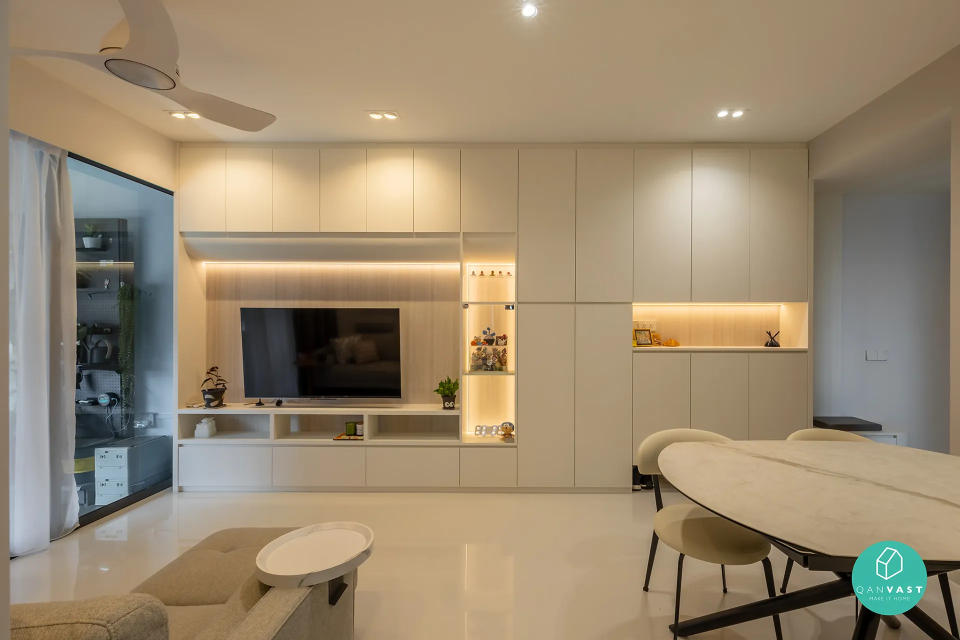 An elegant open-plan living and dining area at Bartley Ridge with a round marble dining table and upholstered chairs. The image showcases a custom-built entertainment wall with integrated lighting and seamless cabinetry, reflecting a sophisticated urban style.