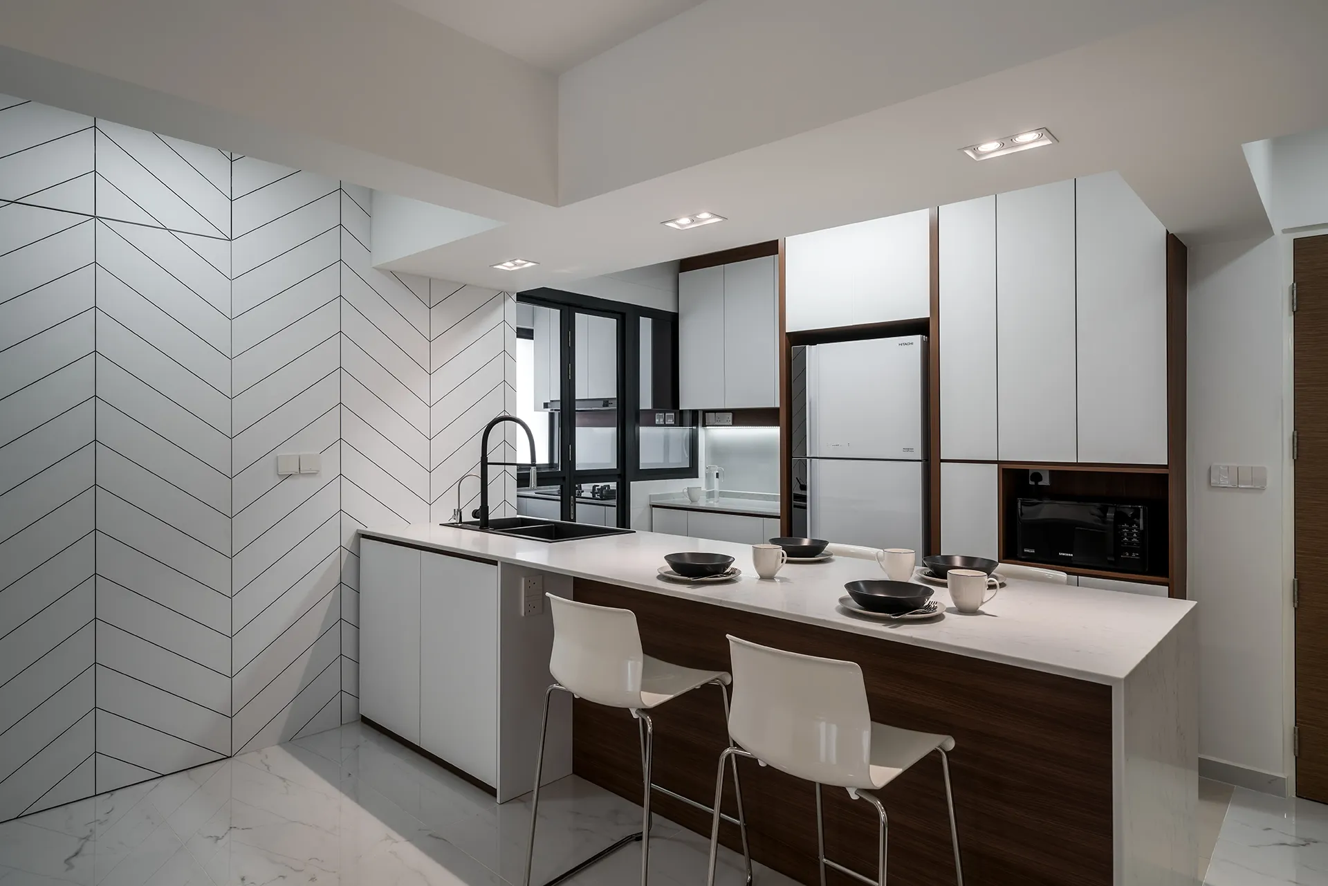 Modern minimalist kitchen in 102B Bidadari Park Drive HDB featuring white countertop island with wooden base, bar stools, chevron backsplash, and marble flooring in Singapore.