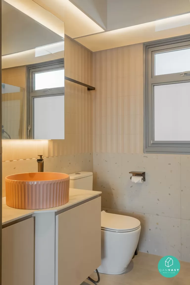 Modern HDB bathroom with unique peach ribbed vessel sink, white vanity, and feature wall using beige vertical tiles and terrazzo accent.