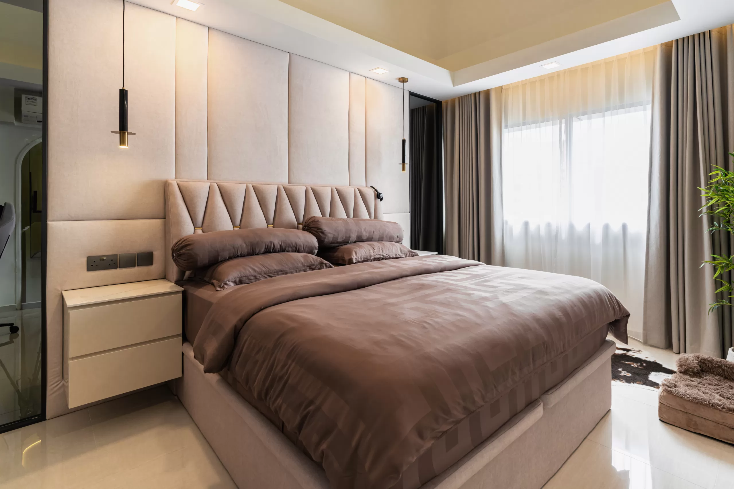 609 Elias Road, 5-room HDB, Modern Luxury master bedroom. Rich brown satin bedding, geometric upholstered headboard, polished flooring, and minimalist pendant lights.