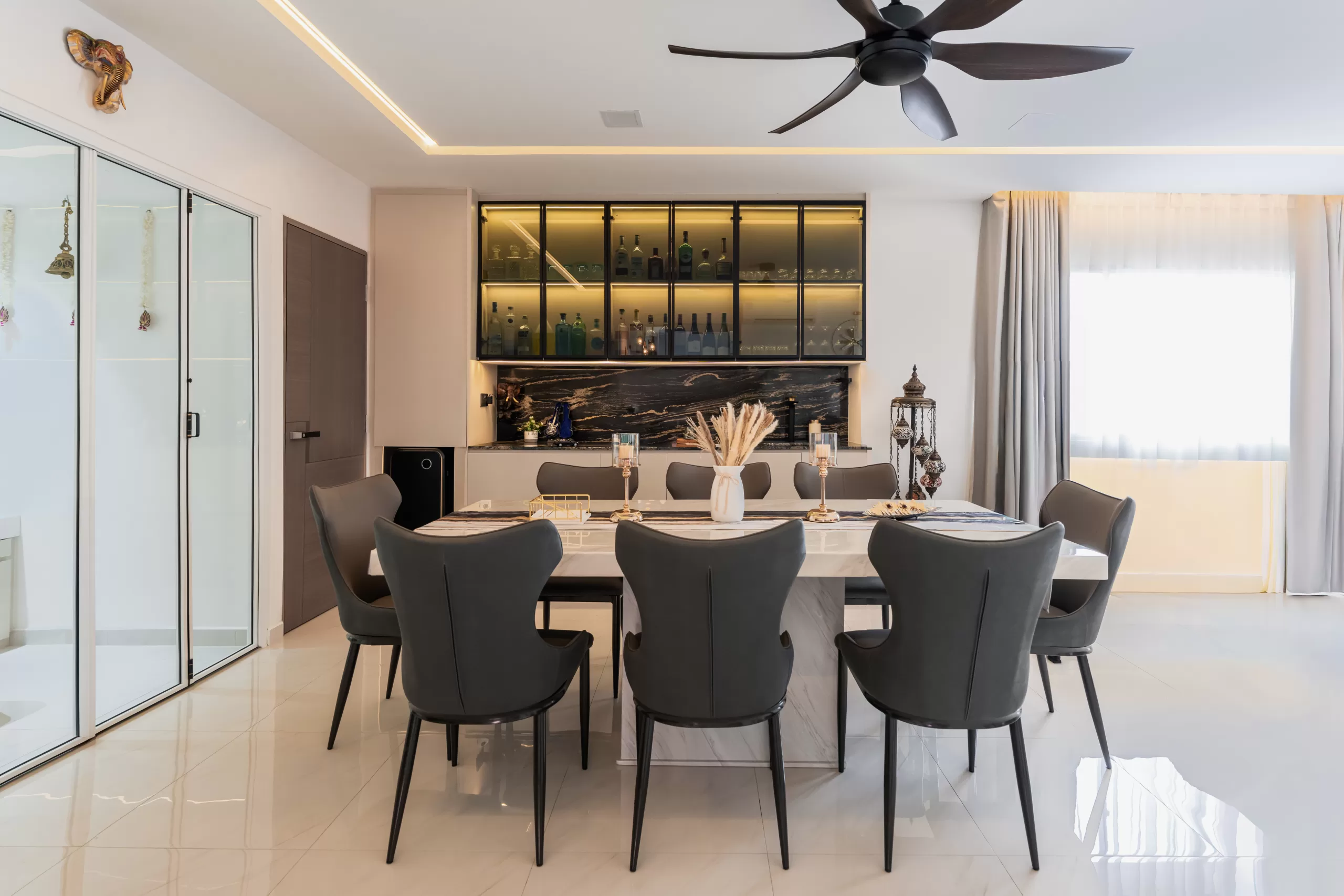 609 Elias Road, 5-room HDB, Modern Luxury dining room. Monochrome design with glossy white table, black upholstered chairs, glass display cabinet lighting, and dark marble backsplash.