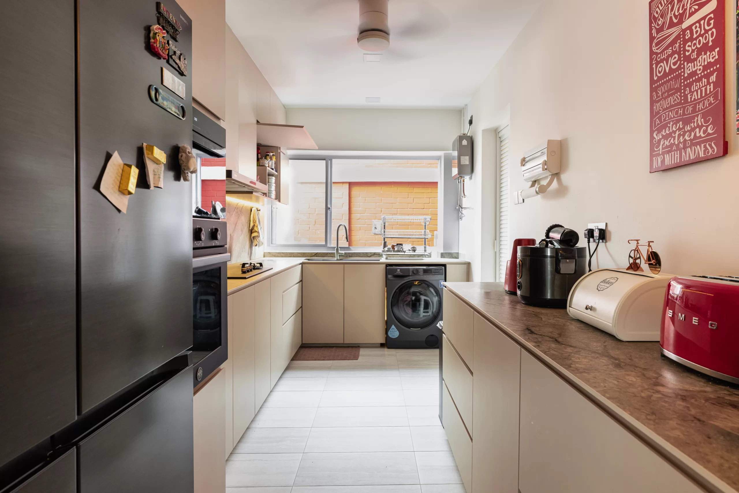 609 Elias Road, 5-room HDB, Modern Luxury galley kitchen. Beige minimalist cabinets, dark countertop, vertical oven stack, and vibrant red SMEG toaster accent.