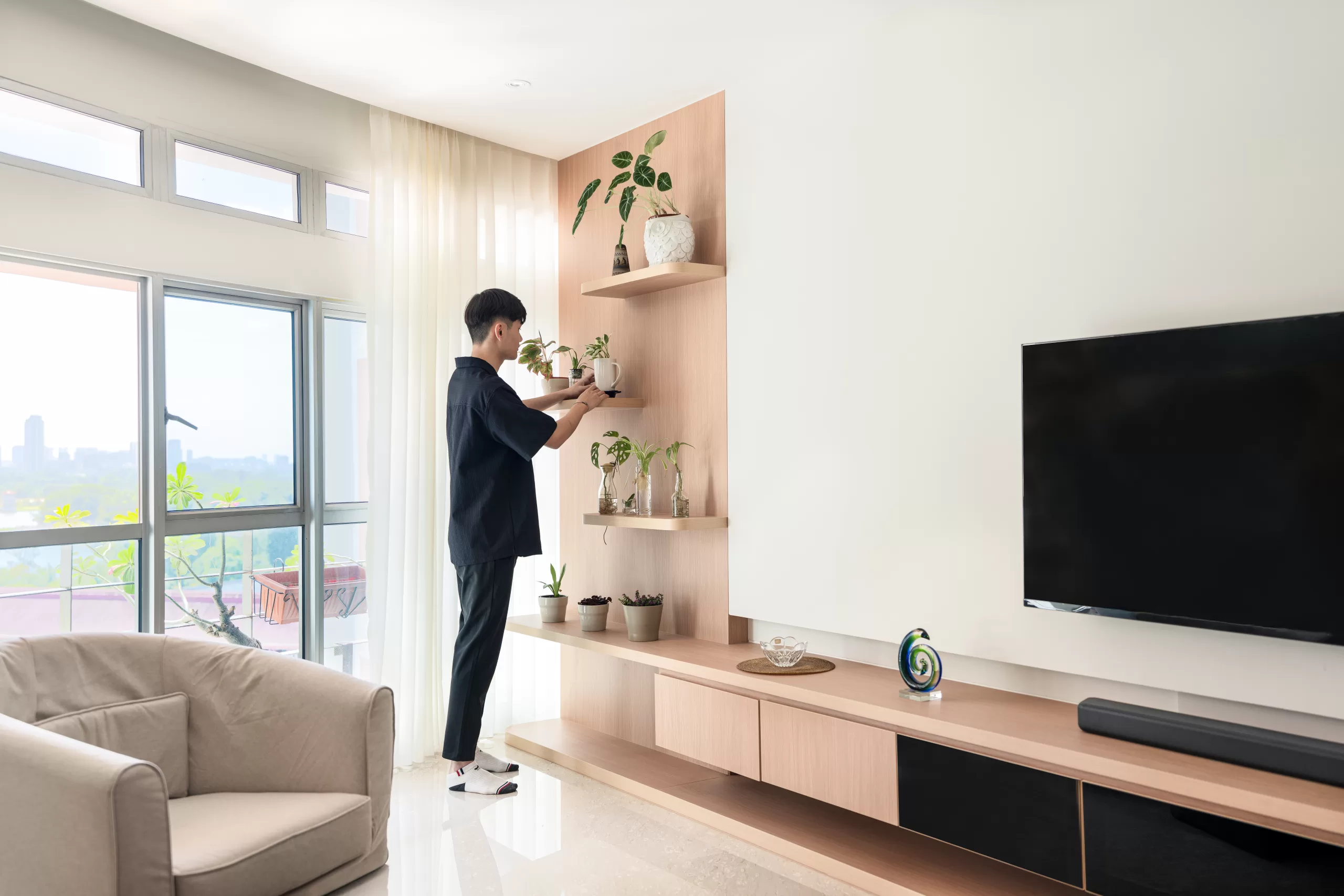 Biophilic Japandi living room focusing on wall-mounted wooden shelves with various potted plants and greenery, near a light-colored armchair.
