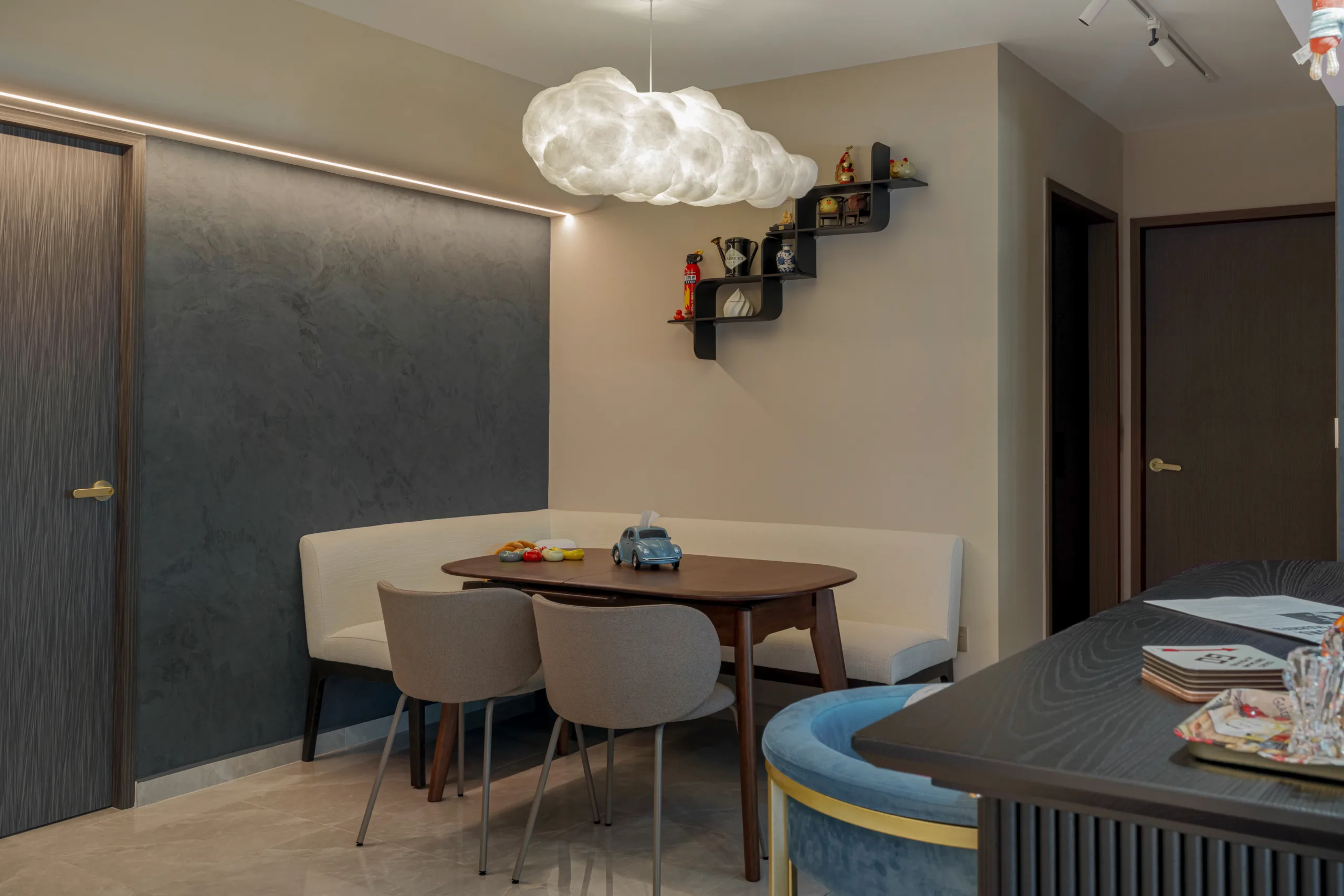 Casual dining nook with a white corner bench, wooden table, and a black zigzag decorative wall shelf.