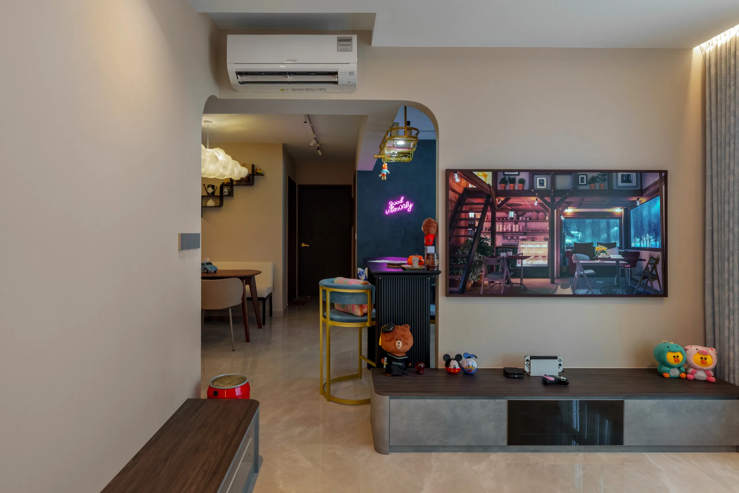 Modern dining space with a "Good Vibes Only" blue neon sign, cloud light, and wall-mounted TV setup.