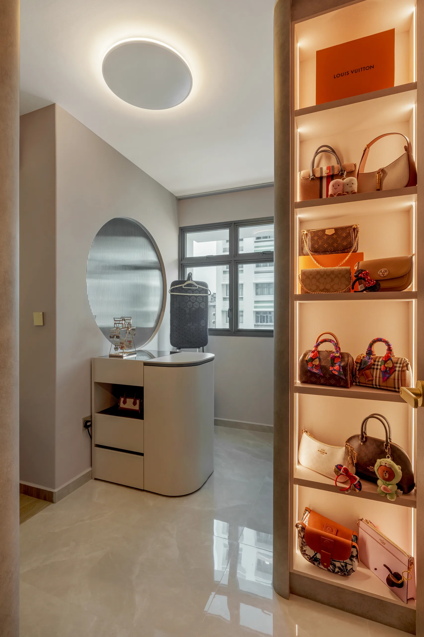 Illuminated built-in shelving for luxury handbag storage with marble flooring in a Singapore HDB walk-in wardrobe.