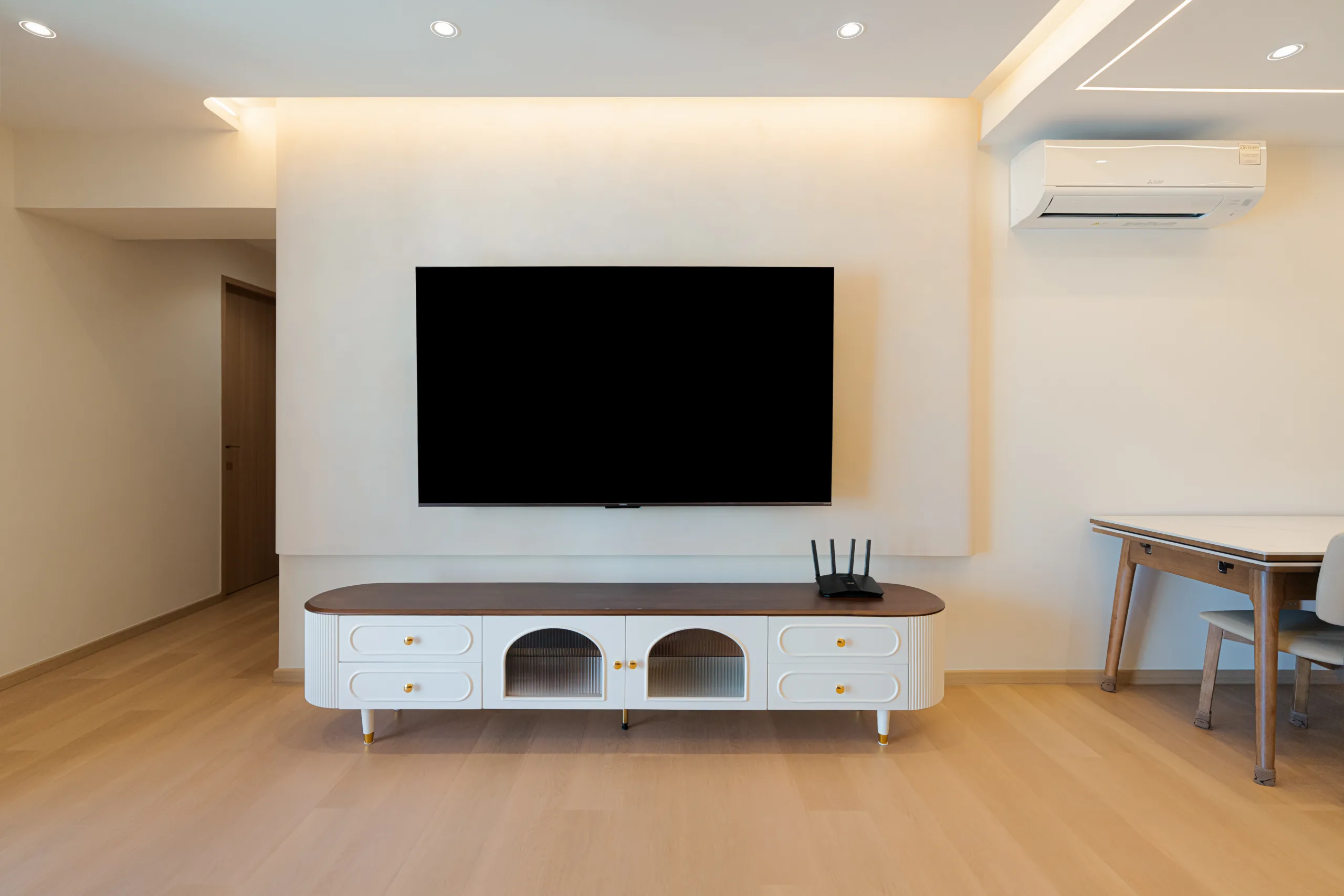 Integrated TV console and study desk with light wood finishes in a minimalist 4-room HDB living room.