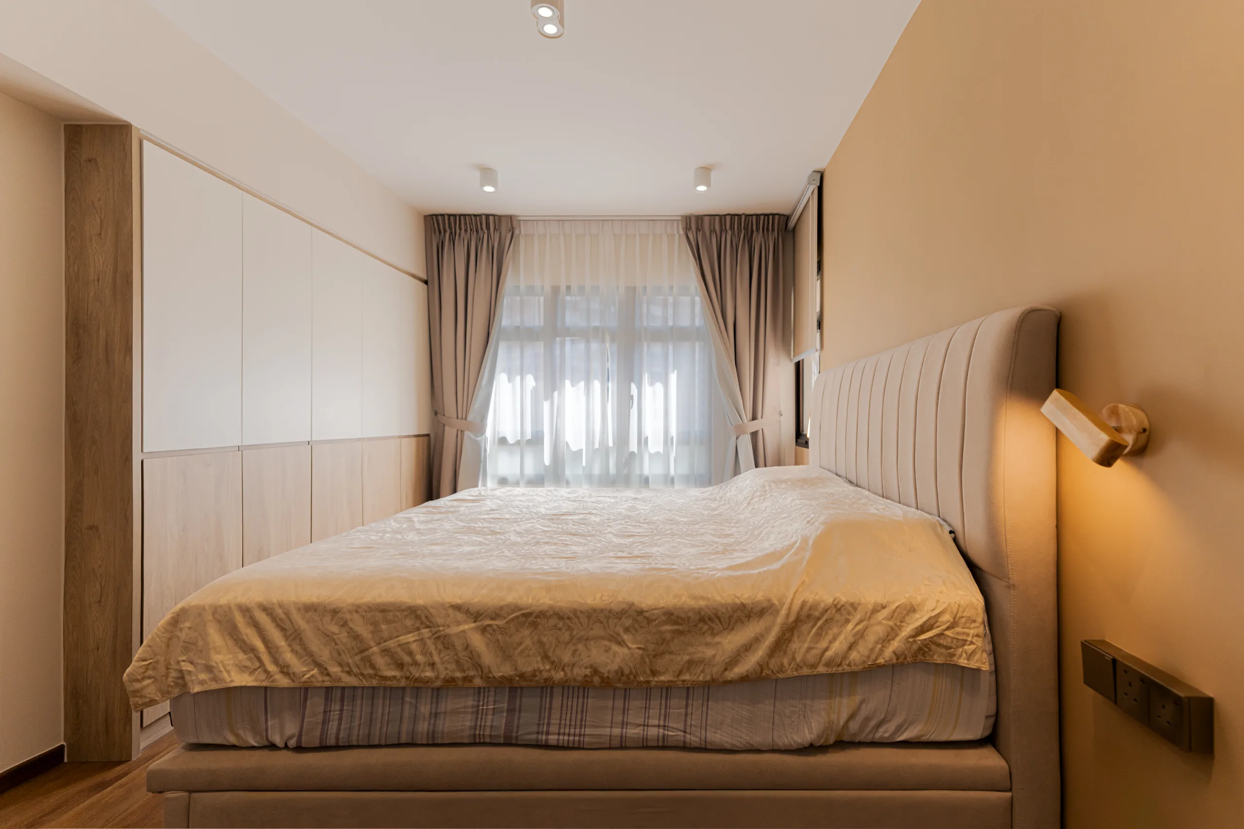 Tranquil master bedroom at 75B Redhill Road with a beige upholstered headboard and warm wood feature wall.