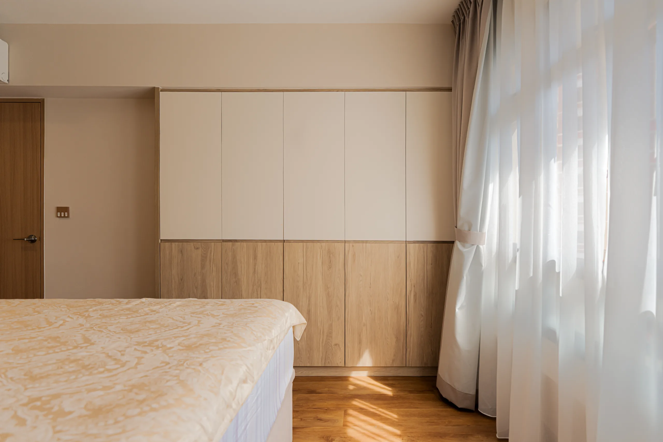 Two-tone floor-to-ceiling built-in wardrobe in a 4-room HDB bedroom using white and light wood laminates.