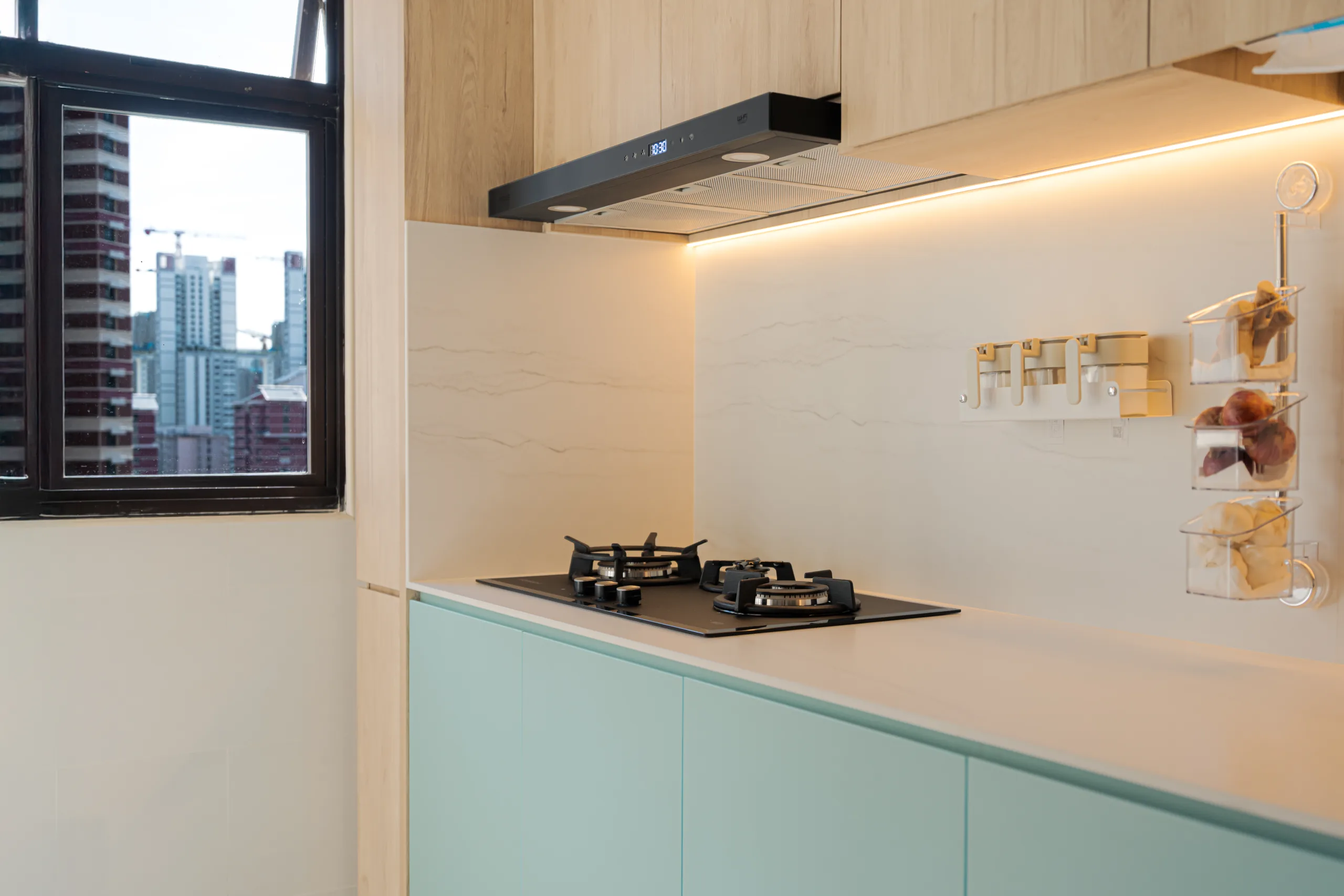 Contemporary HDB kitchen featuring pastel green cabinets, marble-look backsplash, and under-cabinet LED lighting.