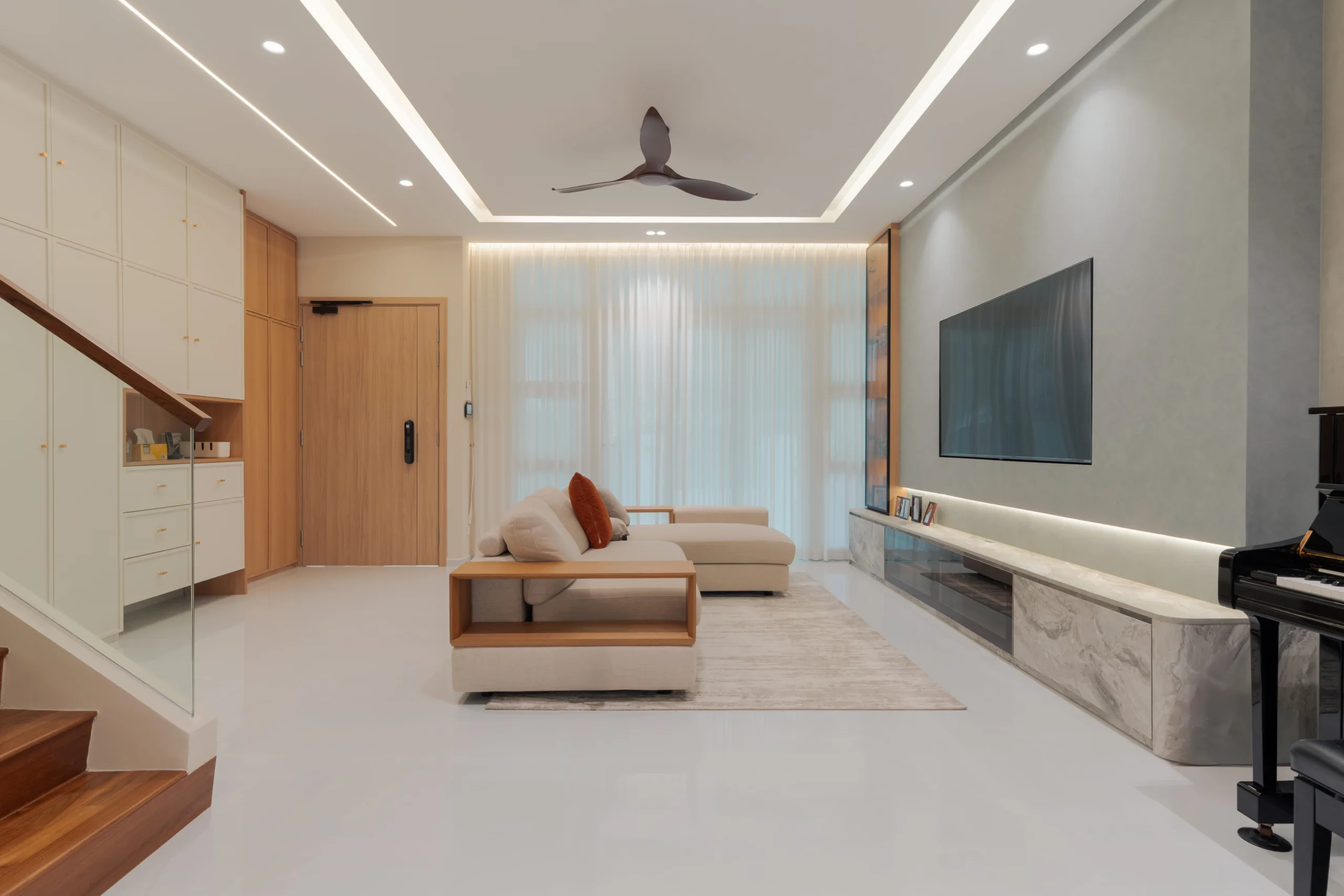 Spacious landed house living room with L-shaped sofa, marble TV feature wall, ceiling fan, and sheer curtains in Jalan Redop home by Zenith Arc Singapore