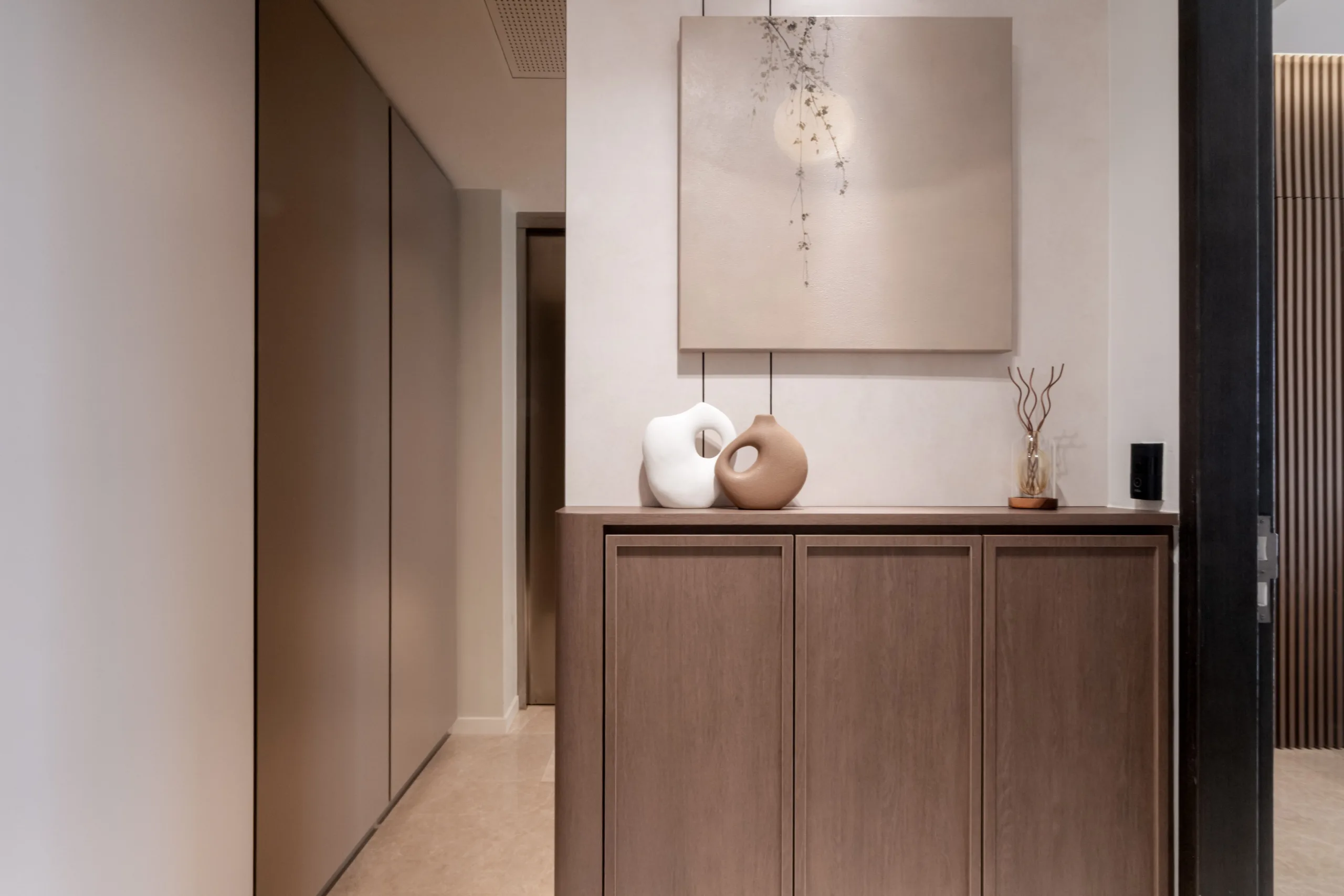 Oak entry console styled with hand-formed white and terracotta ceramic vases below a textured plaster artwork in a wabi-sabi condo foyer