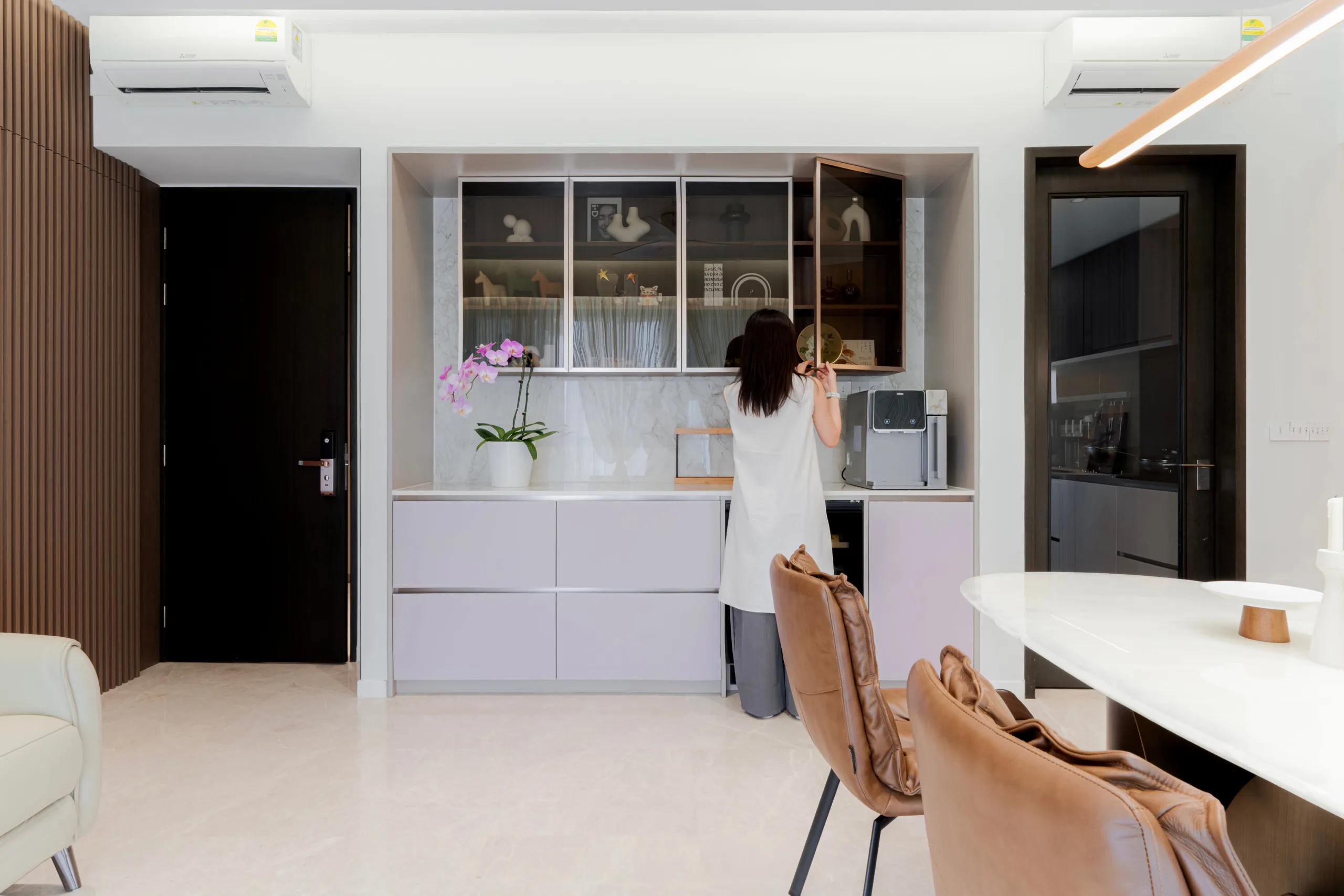 Dry kitchen pantry with soft lilac cabinetry, glass-front display cabinets and a marble backsplash in a wabi-sabi condo
