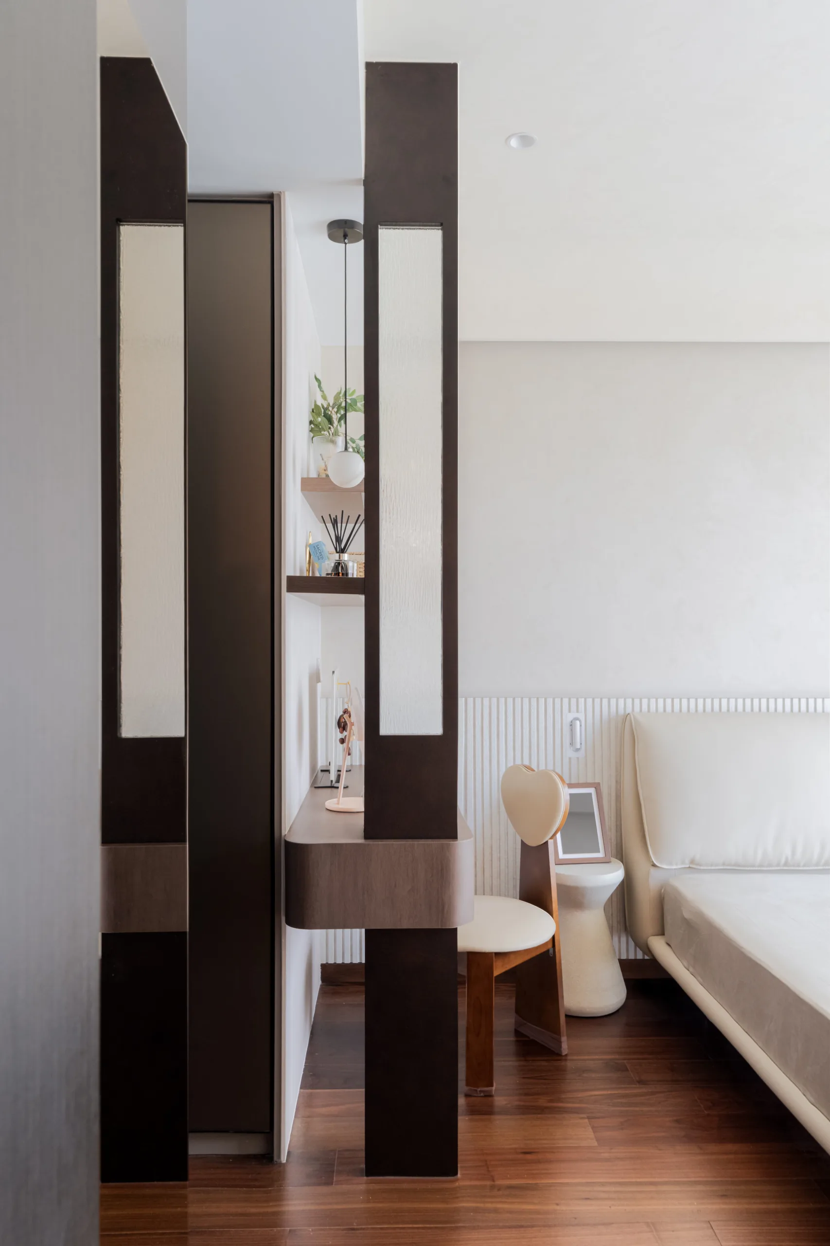 Reeded-glass and timber dressing nook with a floating vanity and heart-backed chair beside the bed in a wabi-sabi bedroom
