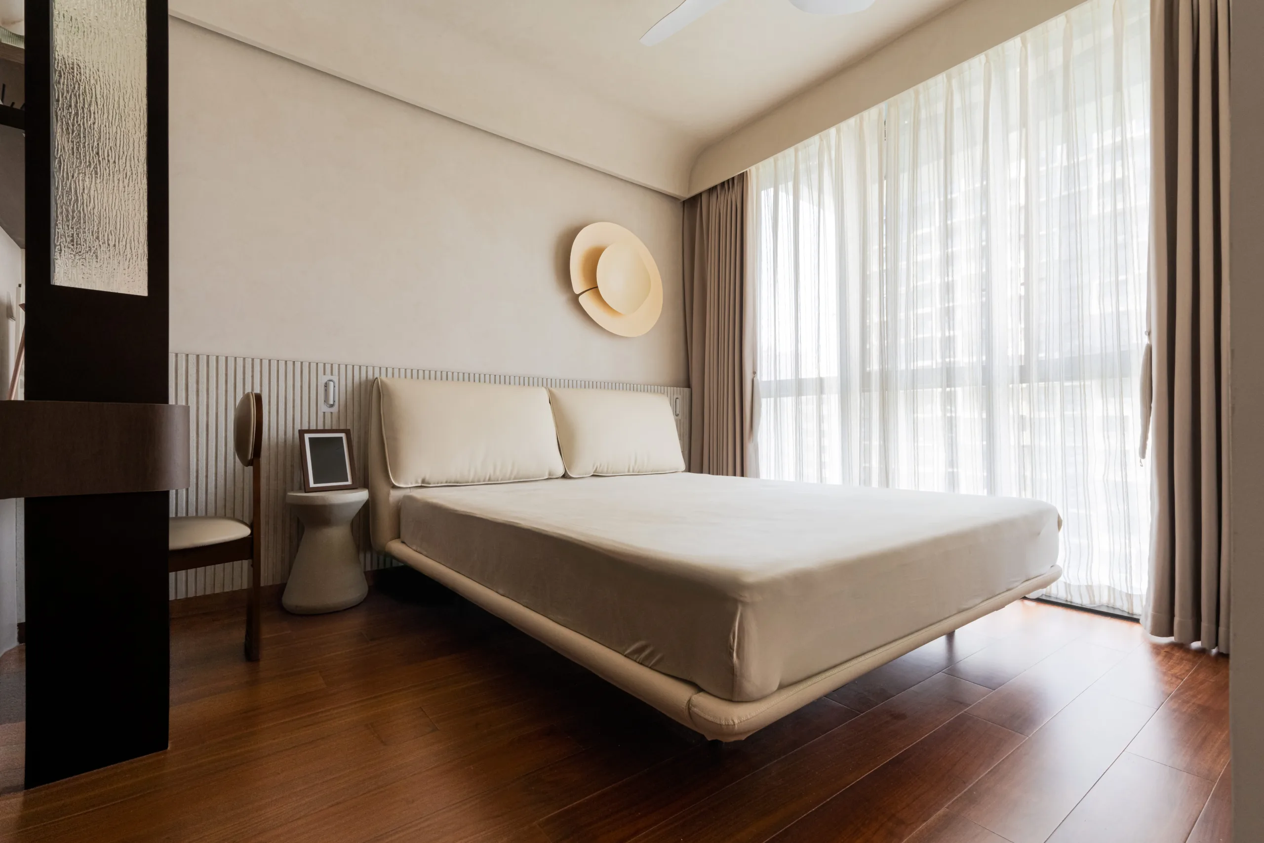 Wabi-sabi master bedroom with a floating cream leather bed, reeded wainscoting and warm walnut flooring at Irwell Hill Residences