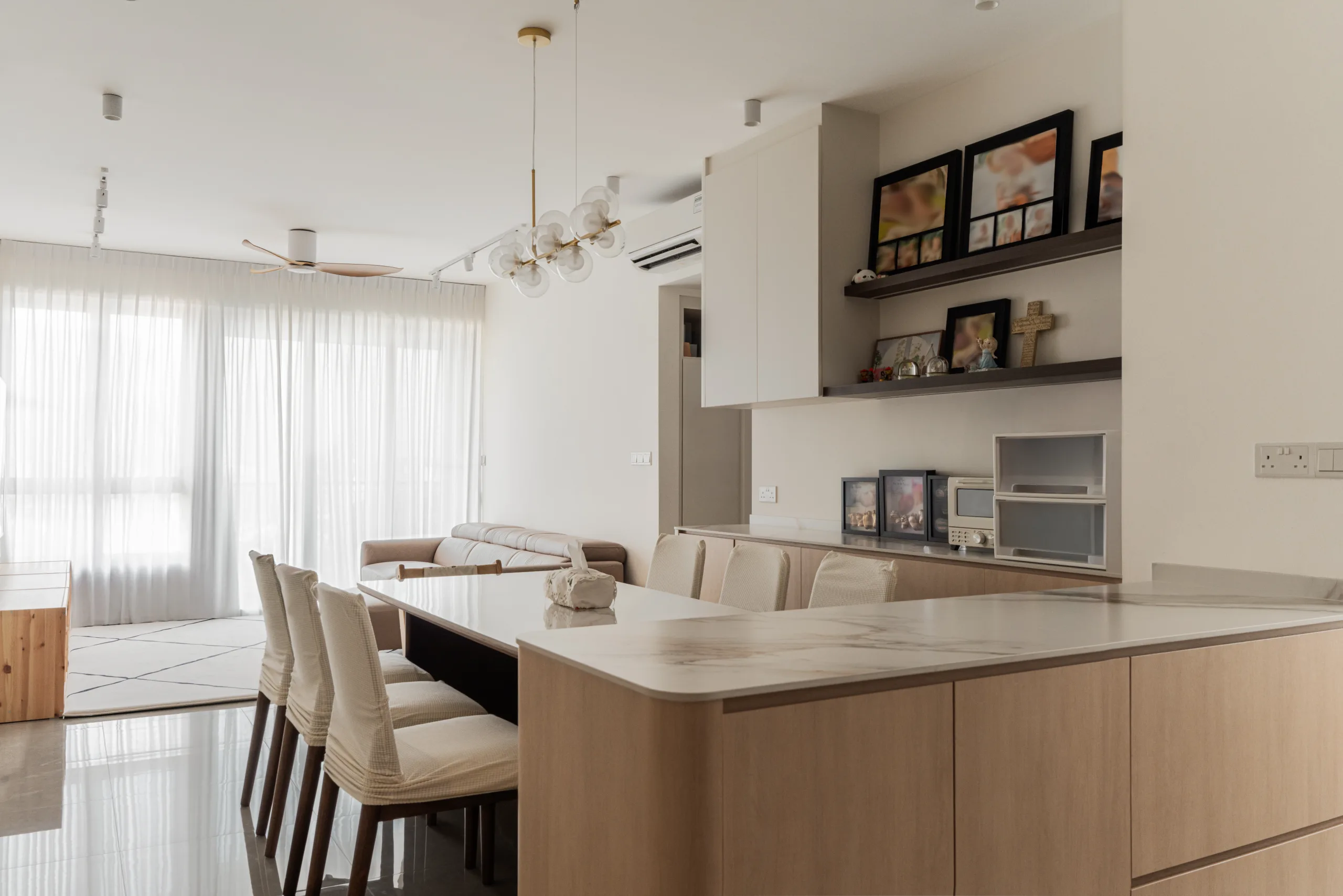 Open-plan dining and kitchen at 21 Kovan Road with a brass-and-glass bubble chandelier and marble-look stone table