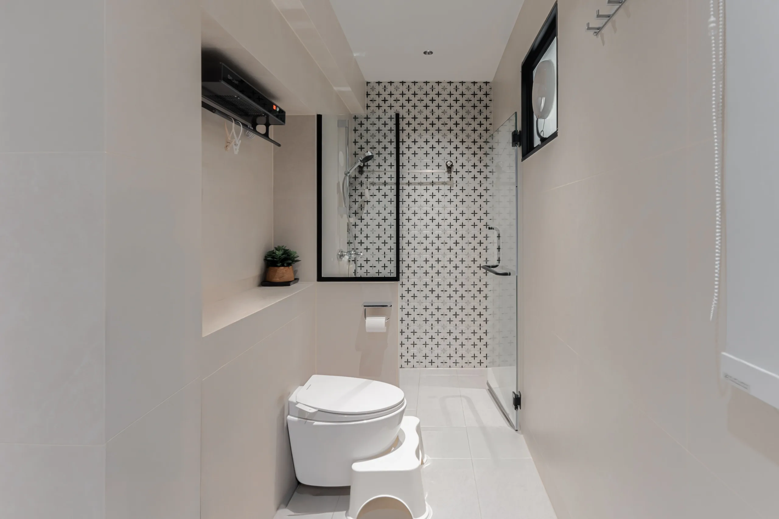 HDB bathroom with Peranakan-pattern feature tile, frameless glass shower screen and wall-hung WC