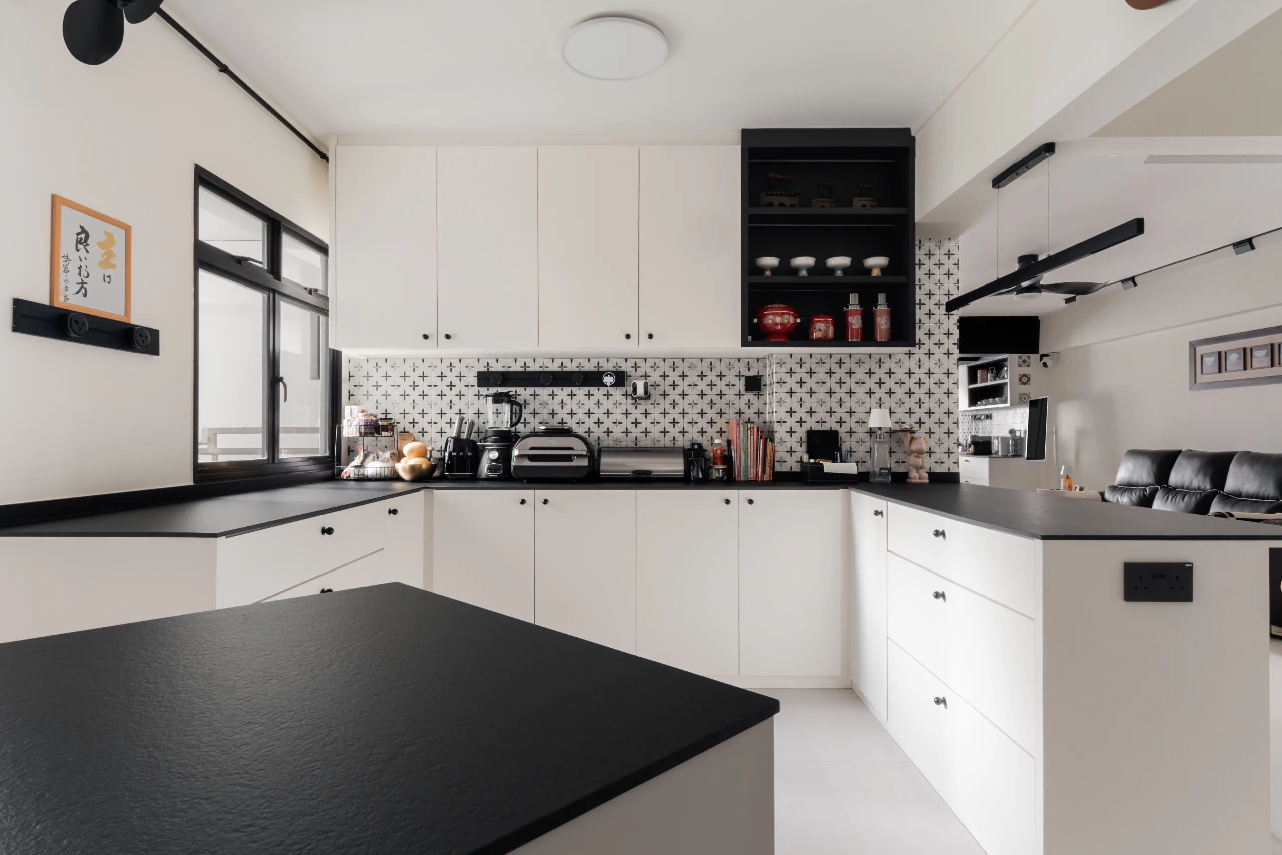 Open L-shaped kitchen with island, black worktops and full-height patterned tile backsplash