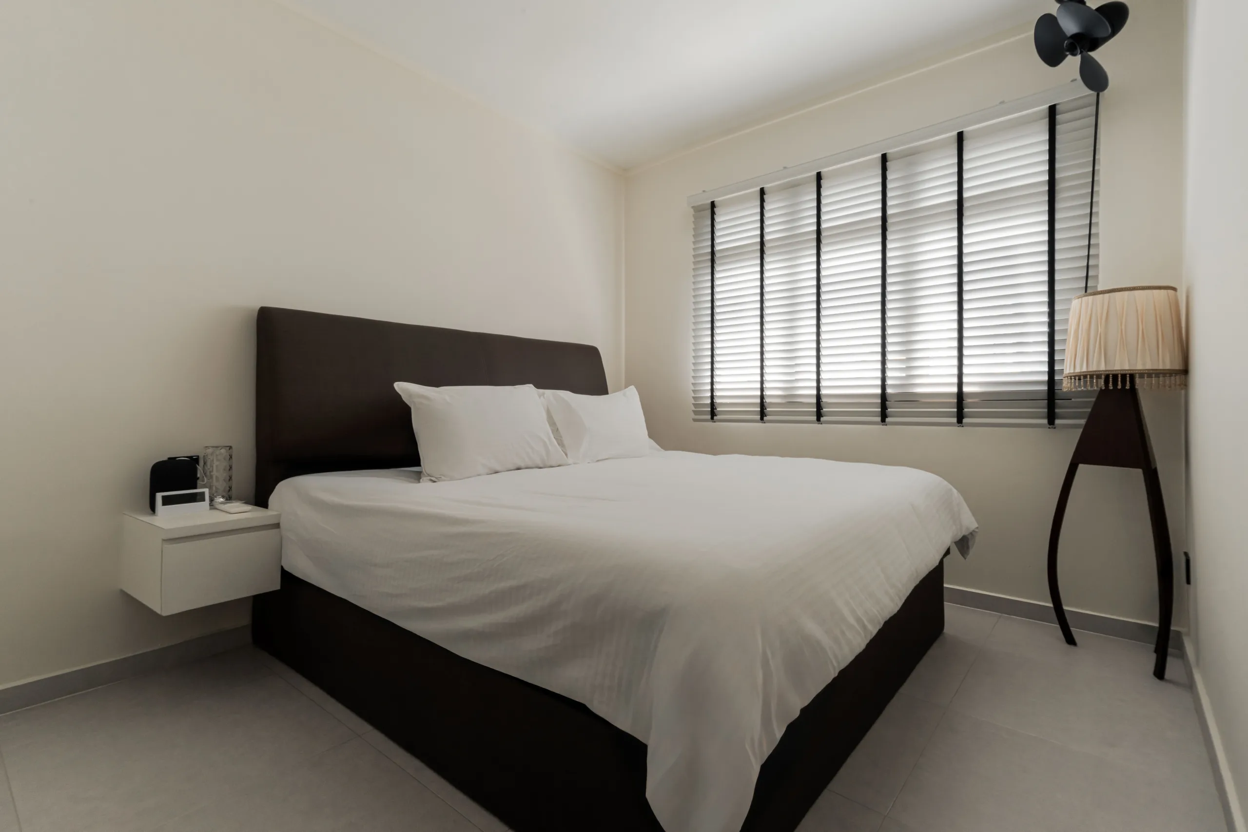 Master bedroom with upholstered headboard, wall-hung nightstand and timber venetian blinds