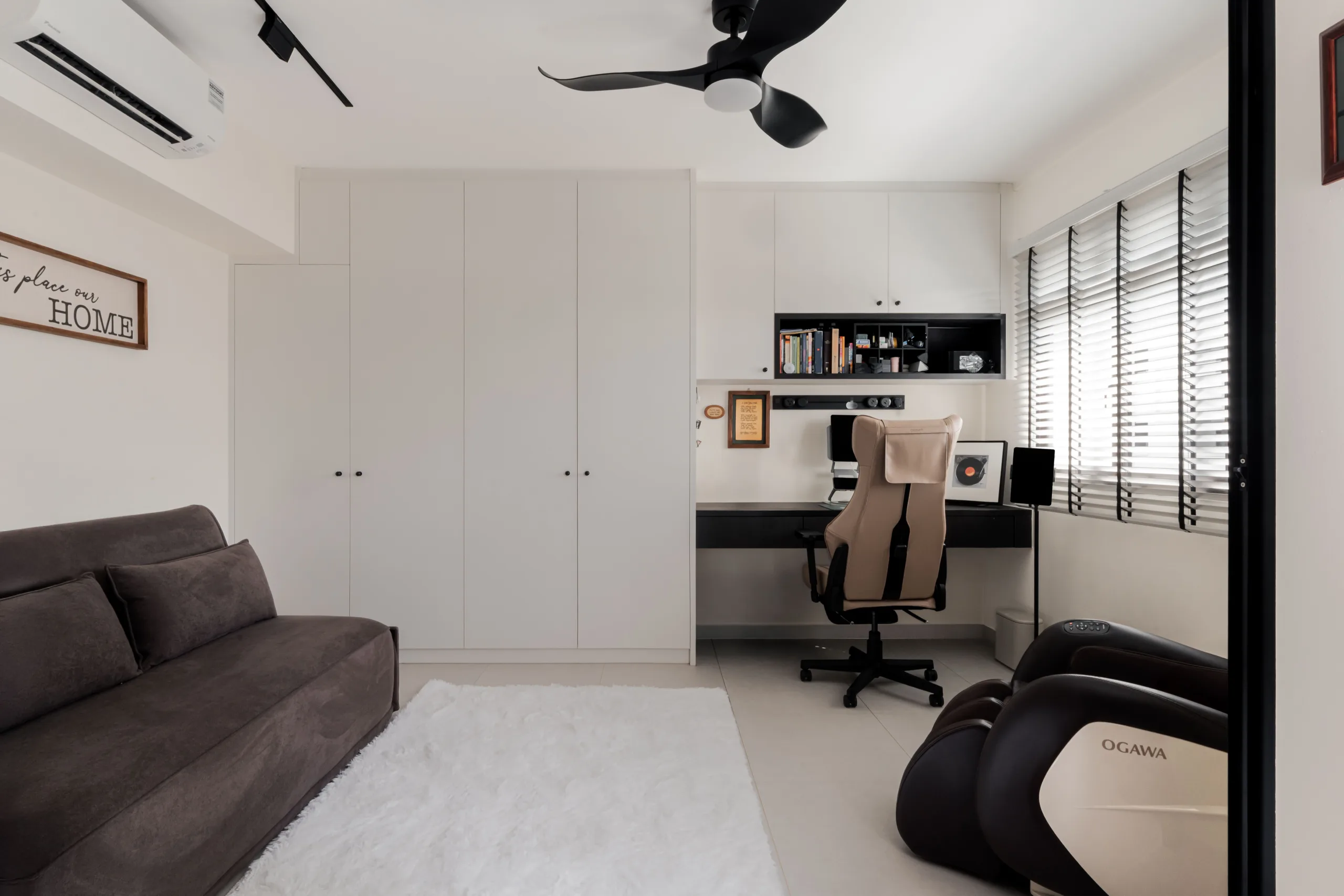 Study and guest room with built-in black desk, full-height white wardrobes and sofa bed in a Woodlands HDB executive apartment