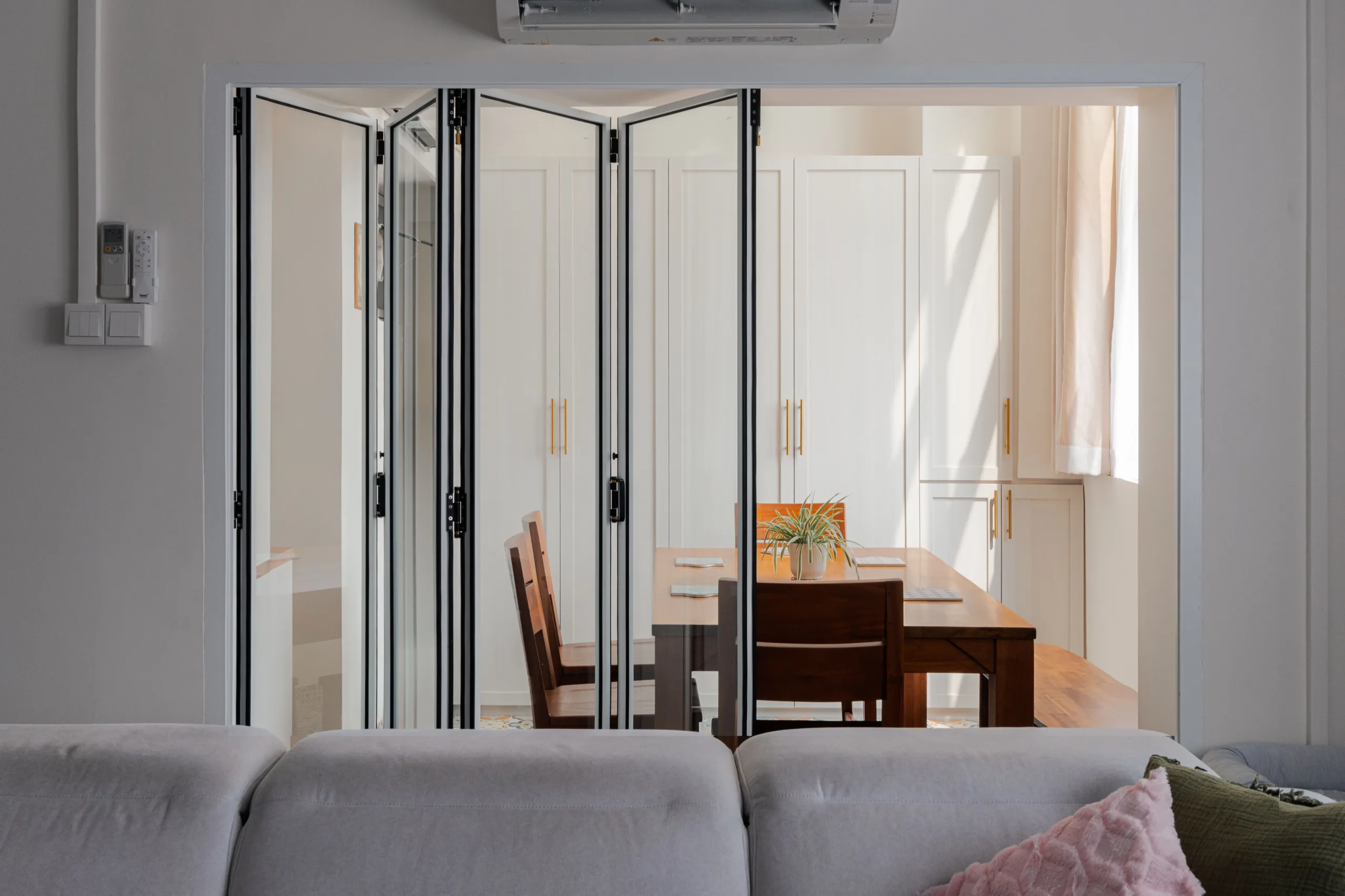 Black-framed glass folding door separating the living and dining rooms