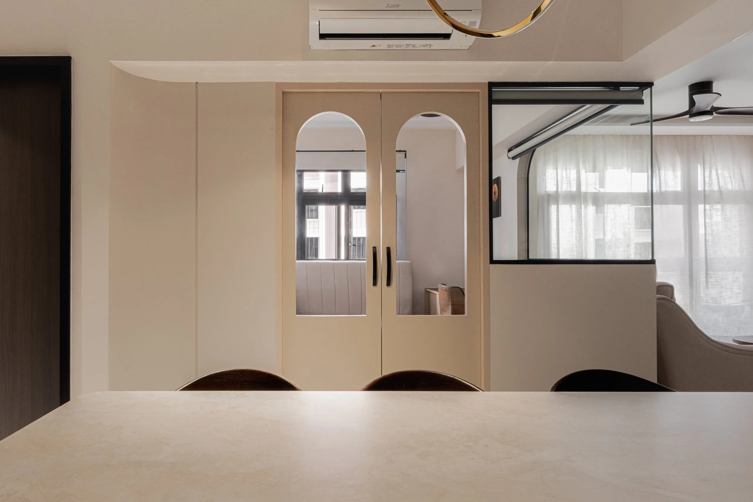 Arched double doors with glass panels and a glazed partition, seen across the dining island