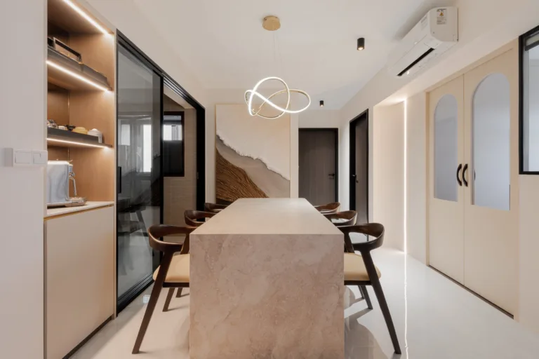 Stone-look dining island with timber chairs under a looped pendant light, beside lit display shelving and arched double doors