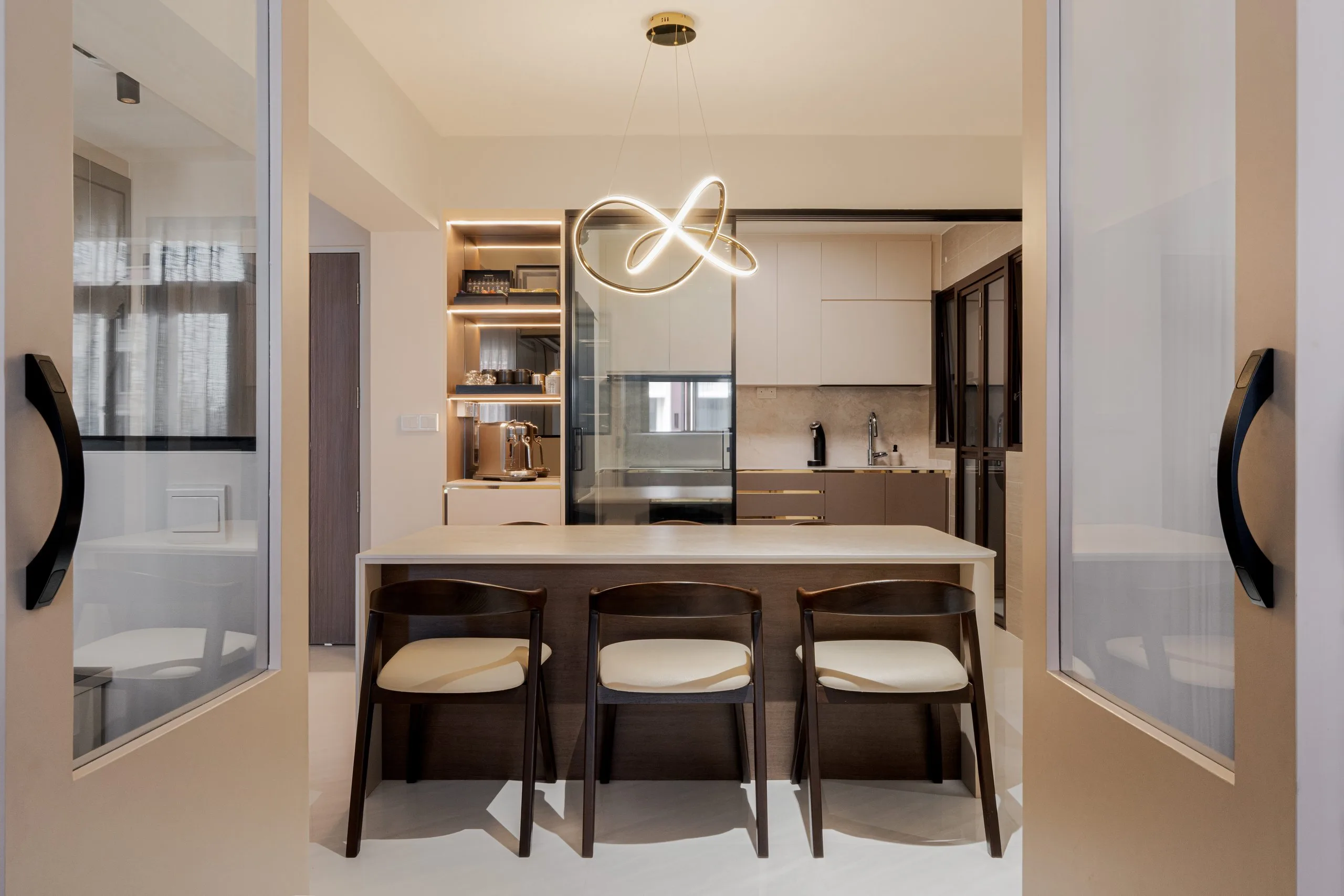 Dining island with three timber chairs, seen through open glass-panelled doors, with the kitchen behind