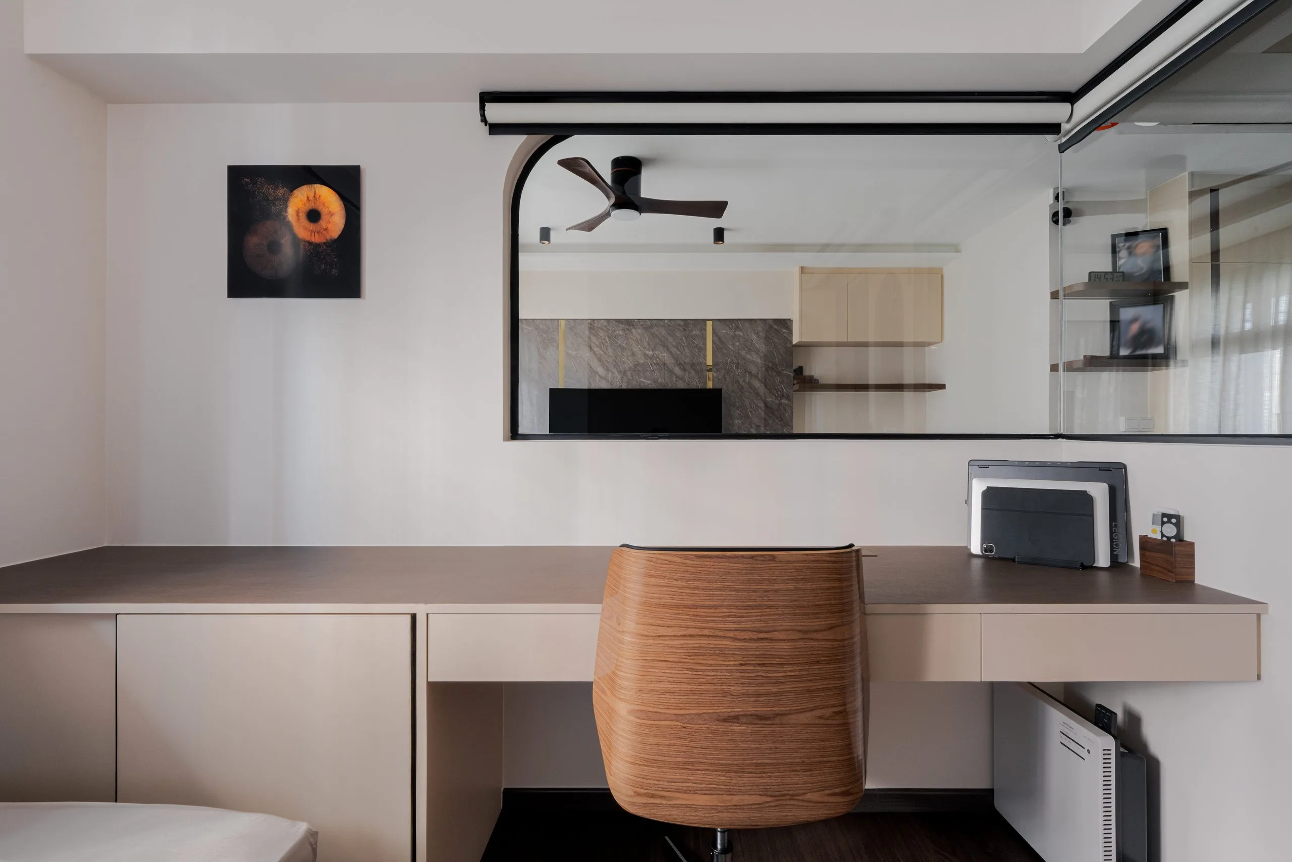 Built-in study desk with drawers below a fixed glass panel that looks into the living room