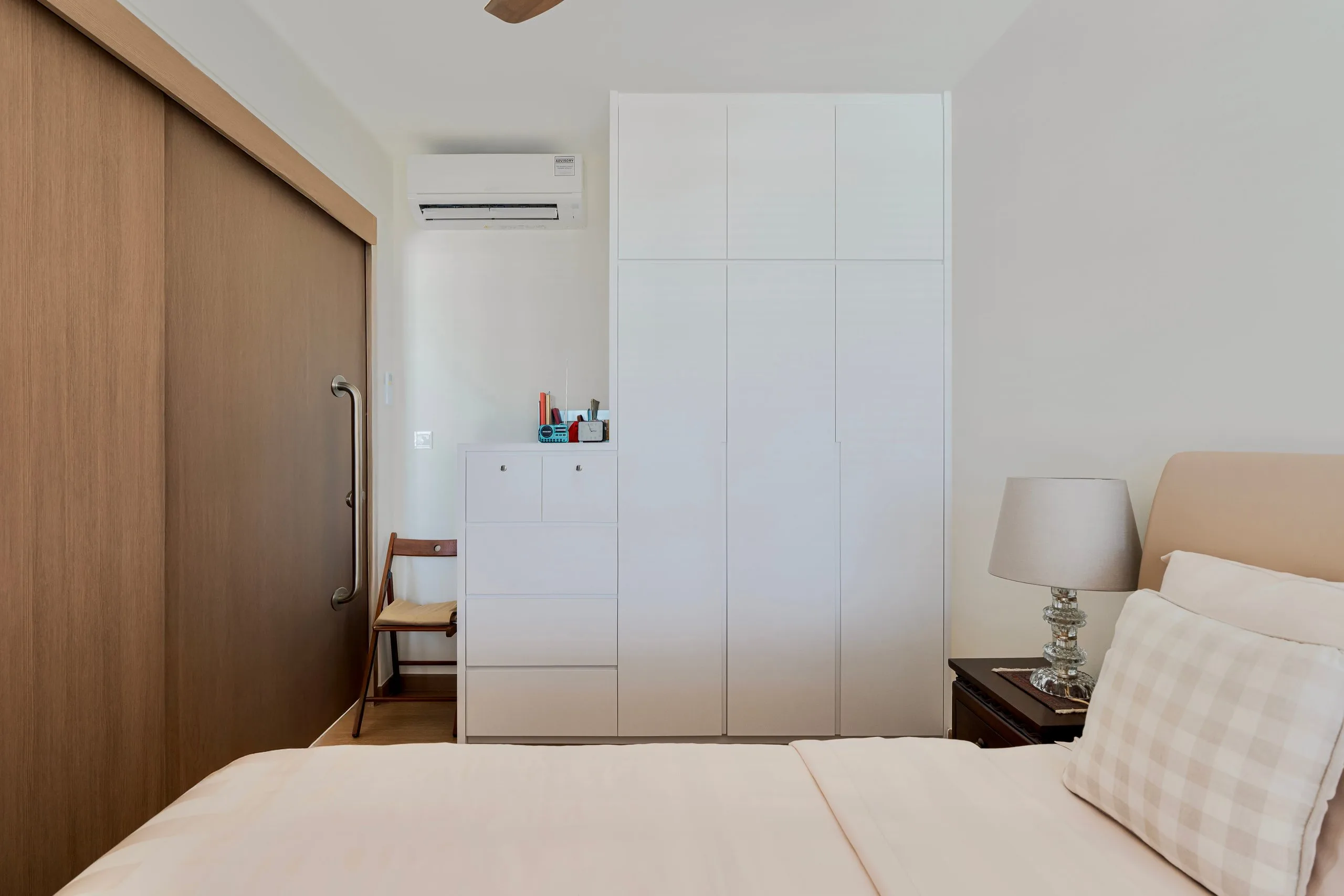 Bedroom with a white full-height wardrobe, a chest of drawers and the timber-look sliding partition