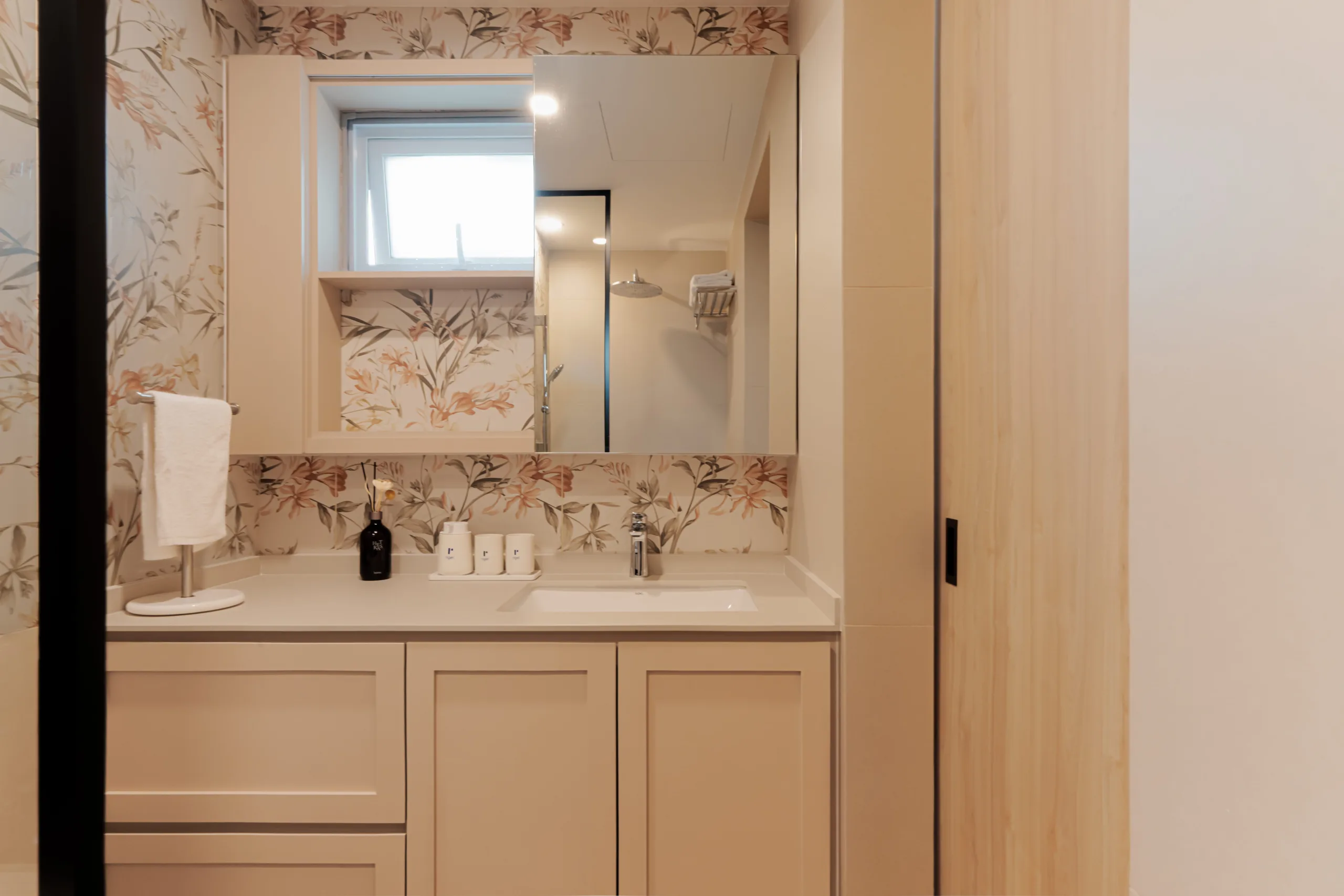 Bathroom vanity at Watercolours EC with cream shaker cabinetry, a mirror cabinet and floral botanical feature tiles
