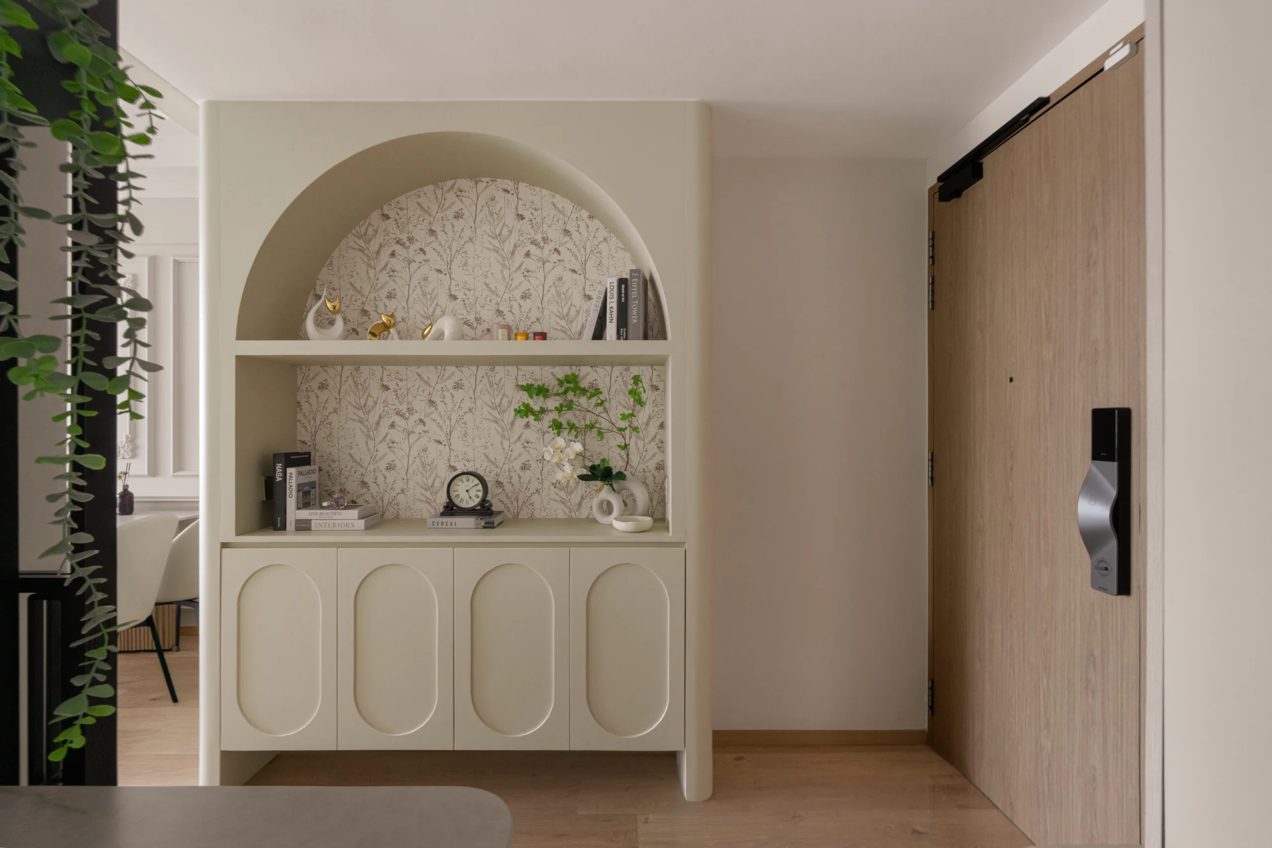Arched entryway alcove at Watercolours EC with a cream console, botanical wallpaper backing and open display shelving