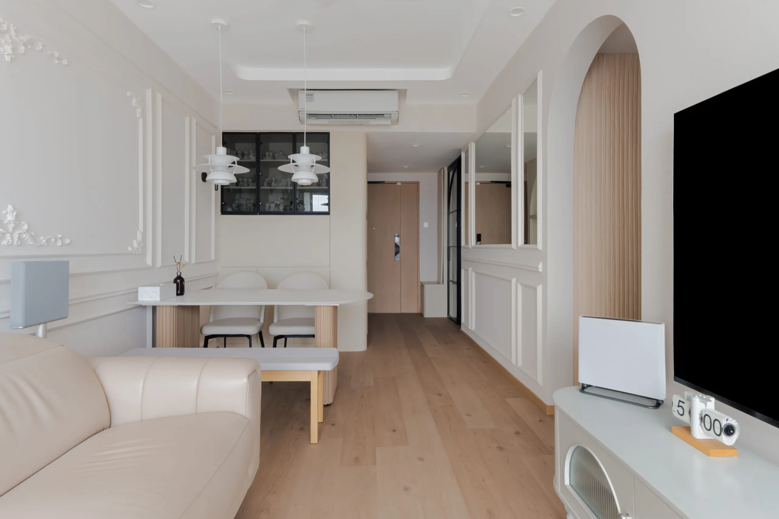 Open-plan living and dining at Watercolours EC with PH5-style pendants, an oval stone dining table and a black-framed glass display cabinet